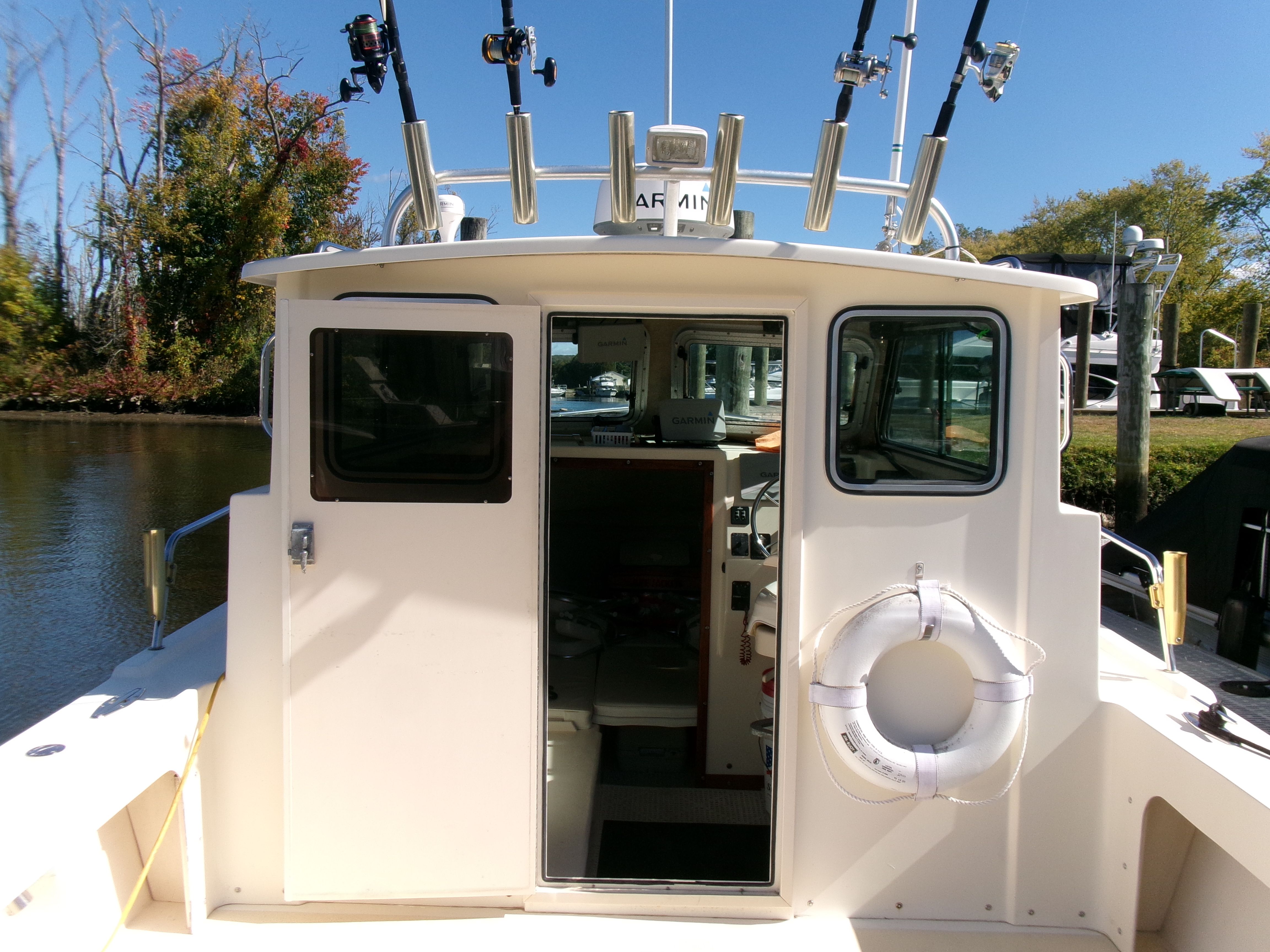 2007 Parker 2520 XL Sport Cabin with fishing rod holders and life ring, docked by the shore.