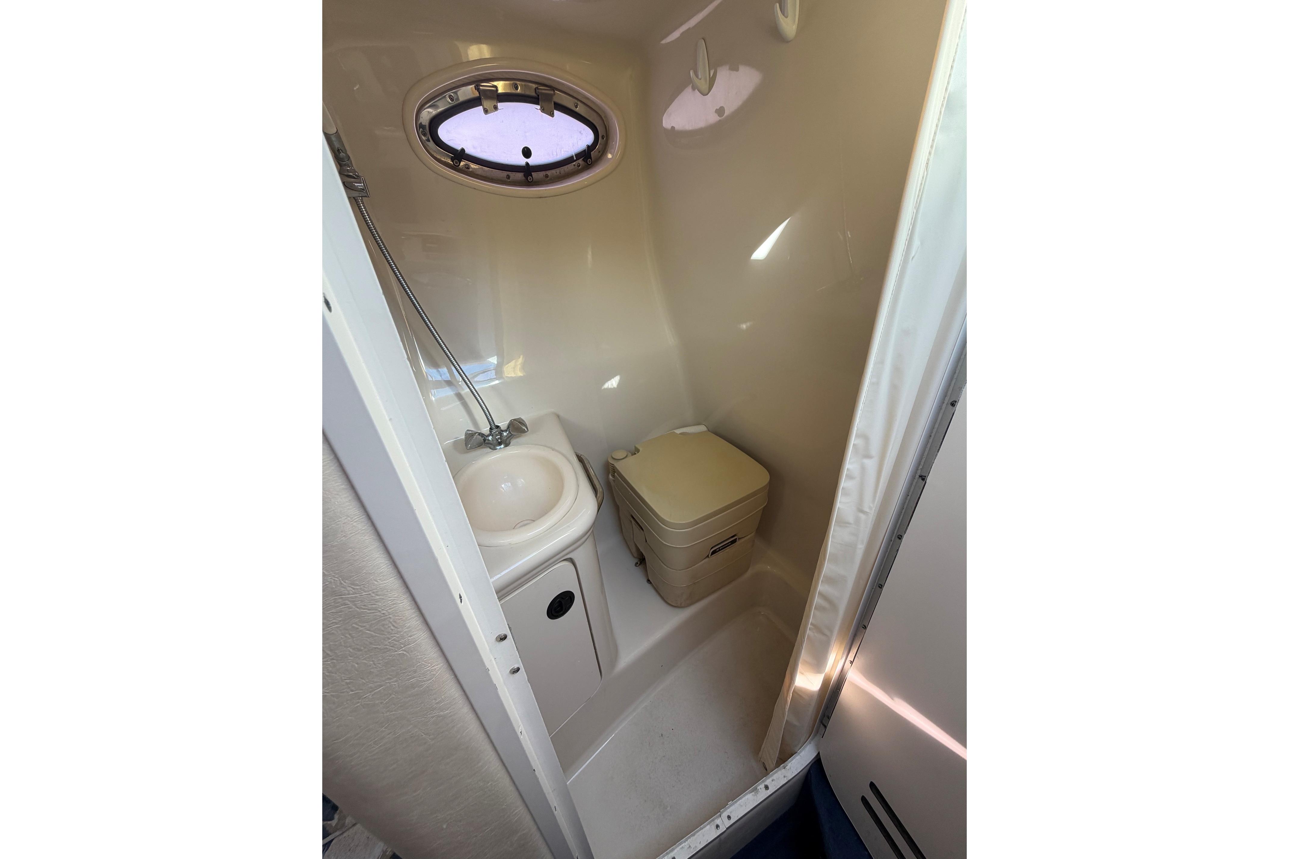 Compact bathroom in 2000 Sea Ray 240 Sundancer boat with sink and toilet.