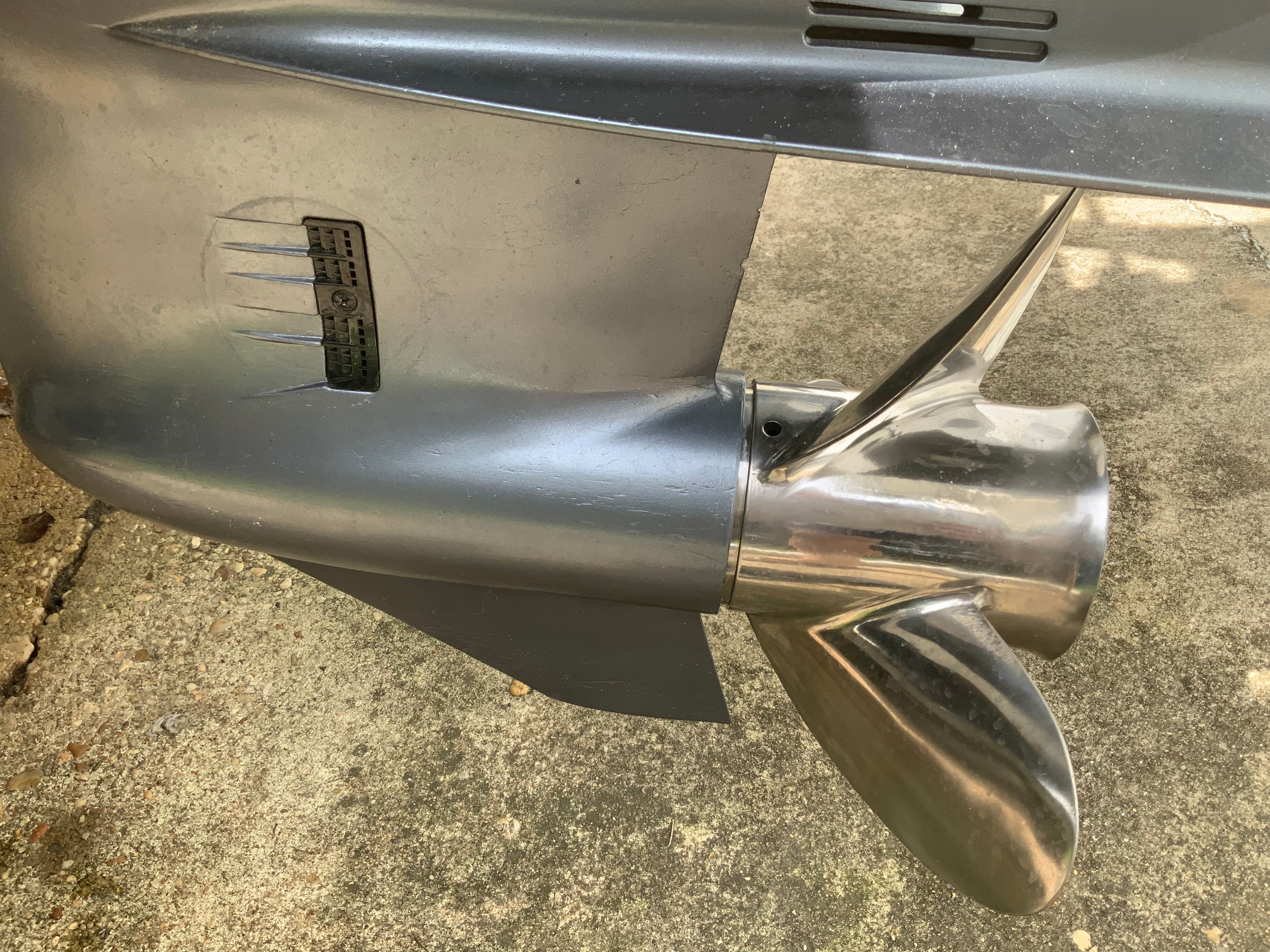 Close-up of a shiny propeller on a boat, resting on concrete.