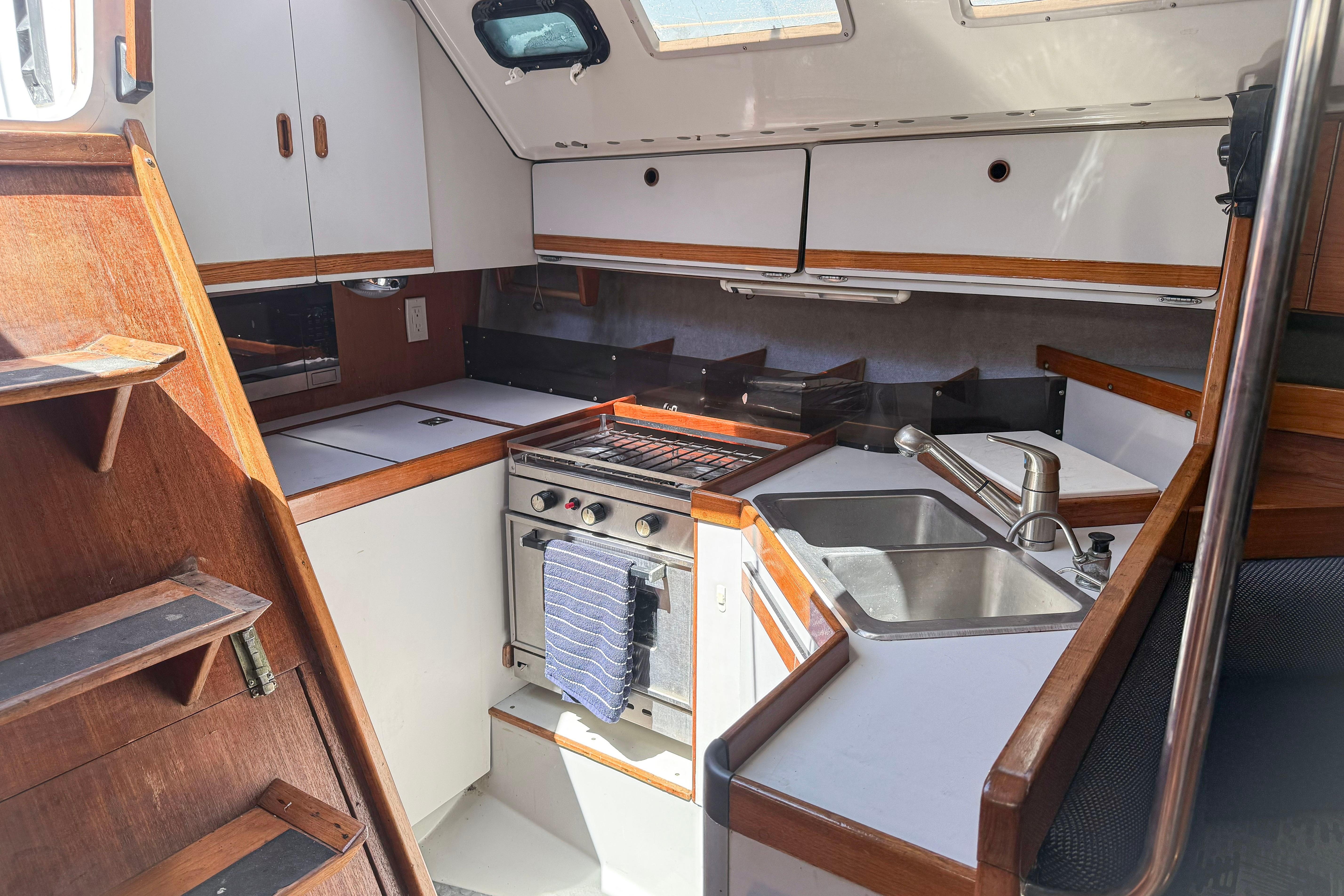 Interior of 1988 Oday 40 sailboat kitchen with stove, sink, and wooden cabinetry.