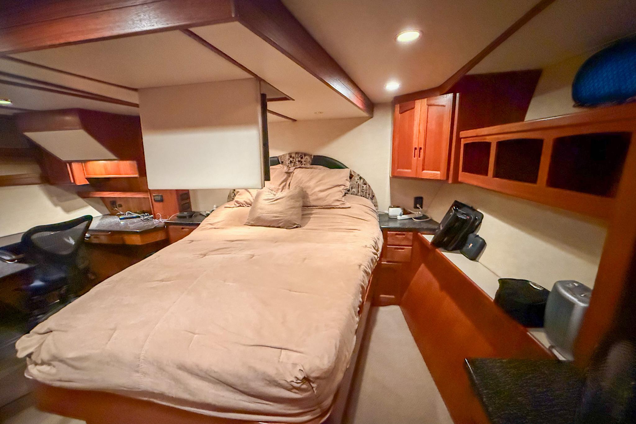 Cozy bedroom interior of 2007 Nordic Tug 54 with wooden cabinetry and desk.