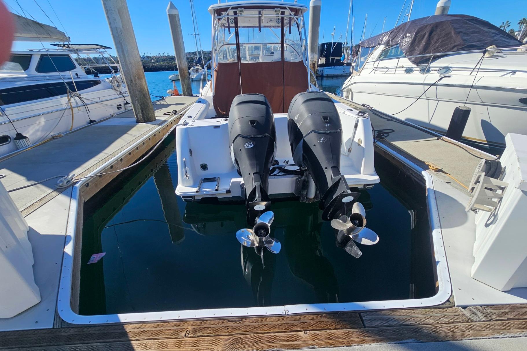 2006 Pro-Line 32 Express boat with dual outboard motors docked at marina.