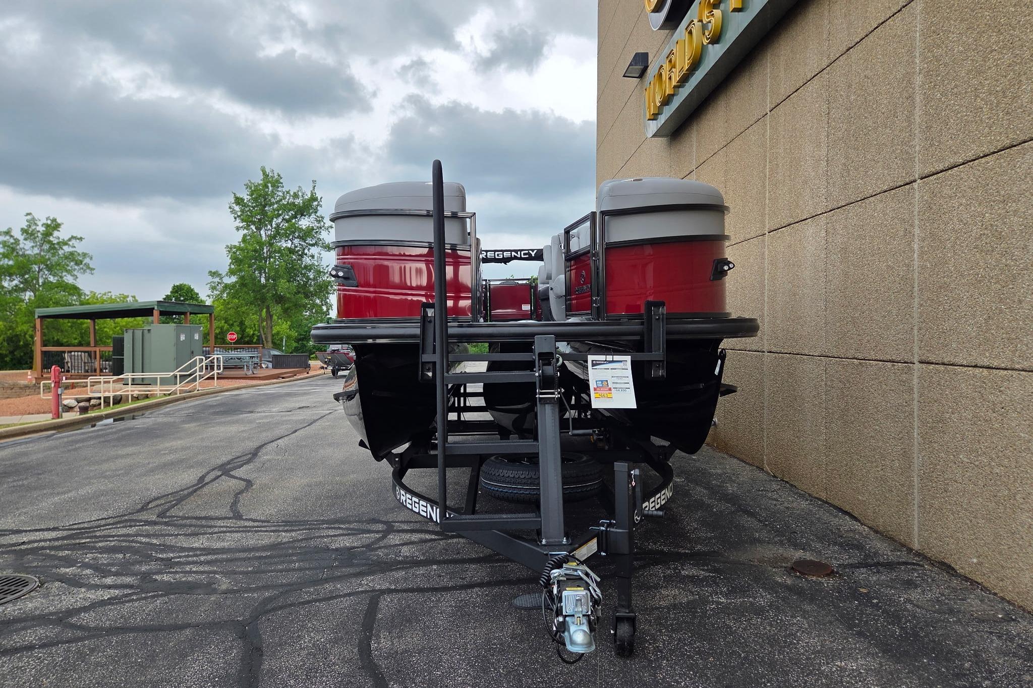 2026 Regency 230 DL pontoon boat on trailer, parked beside a building.