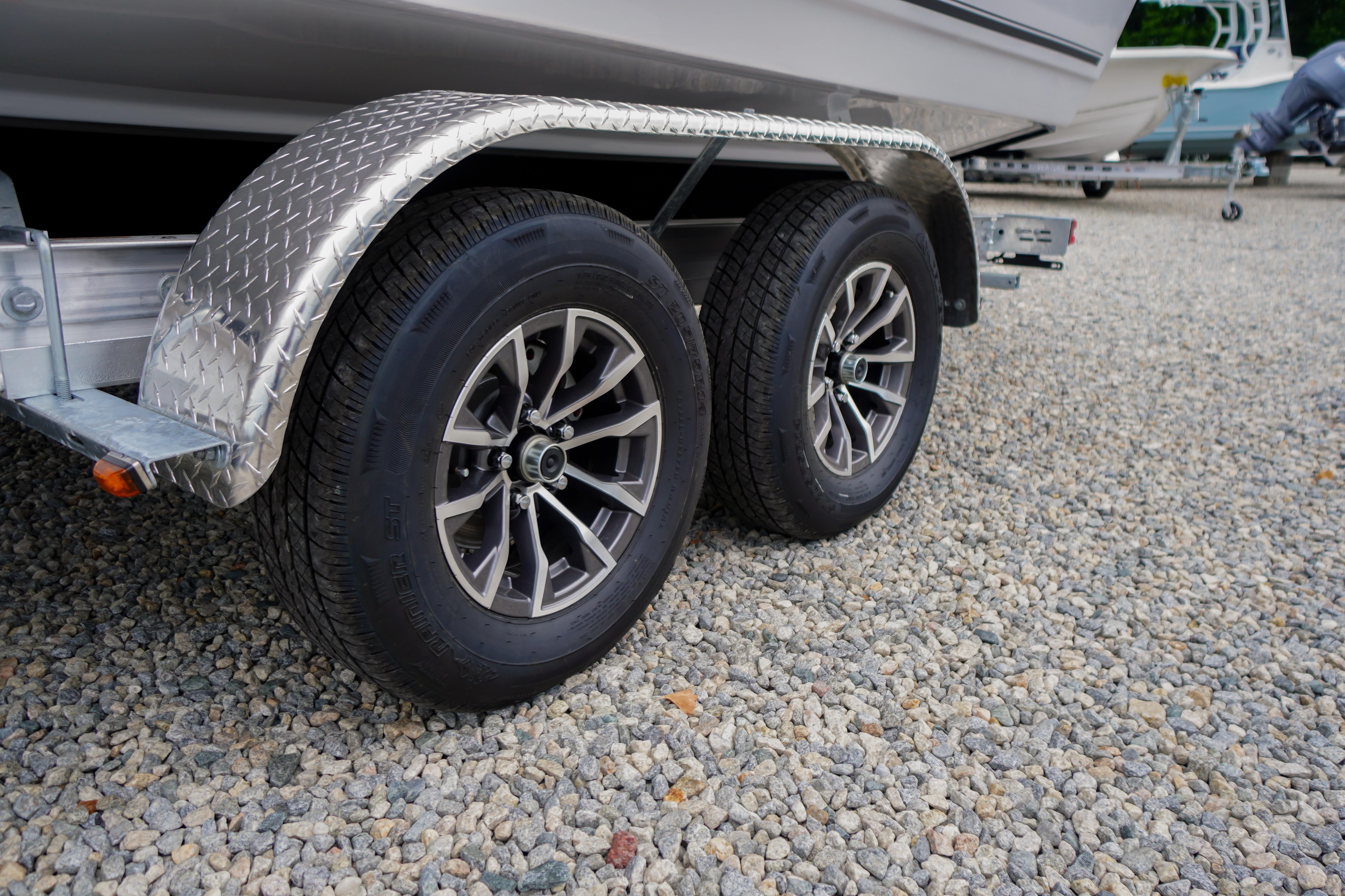 Trailer wheels of a 2026 Tidewater 232 SS boat on gravel surface.