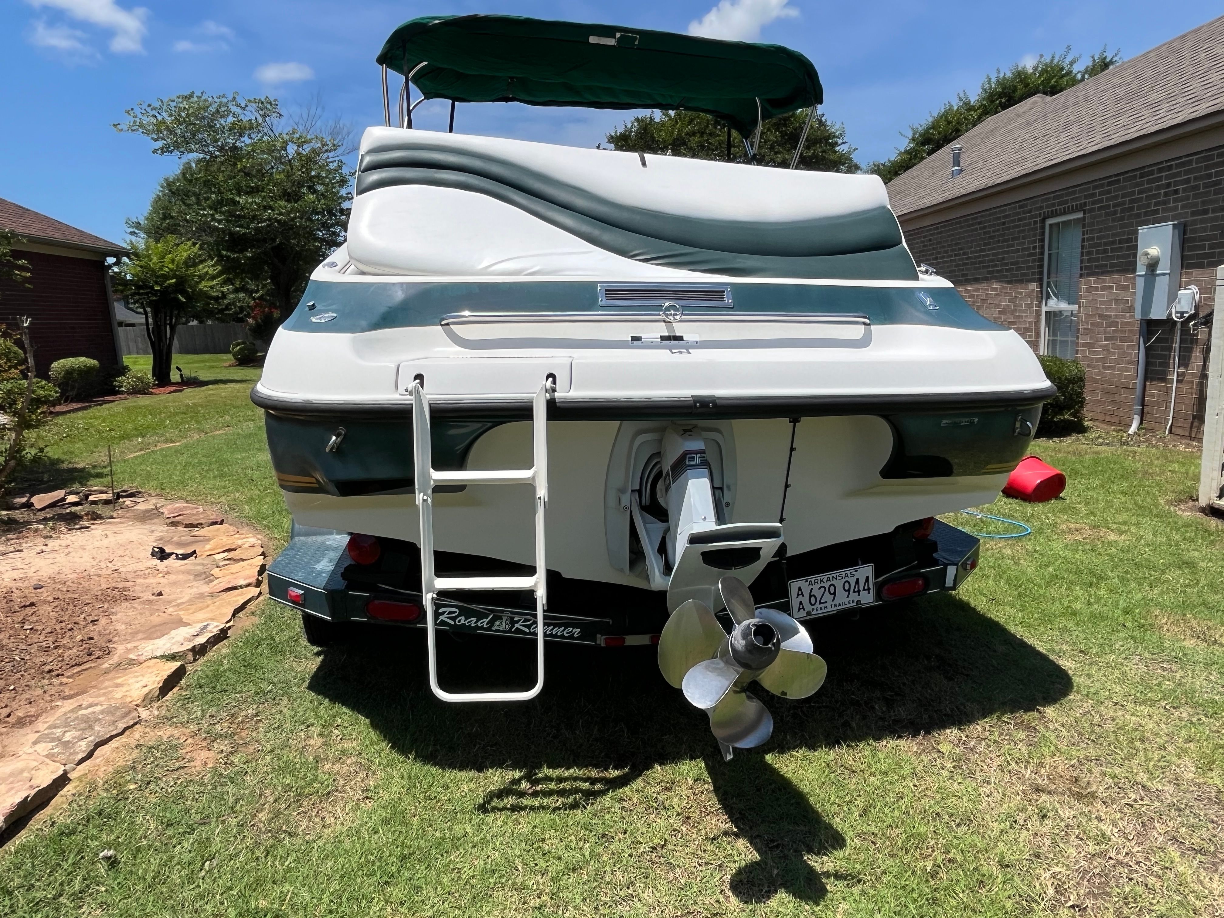 Rear view of a 1996 Crownline 202 BR boat on a trailer in a yard.
