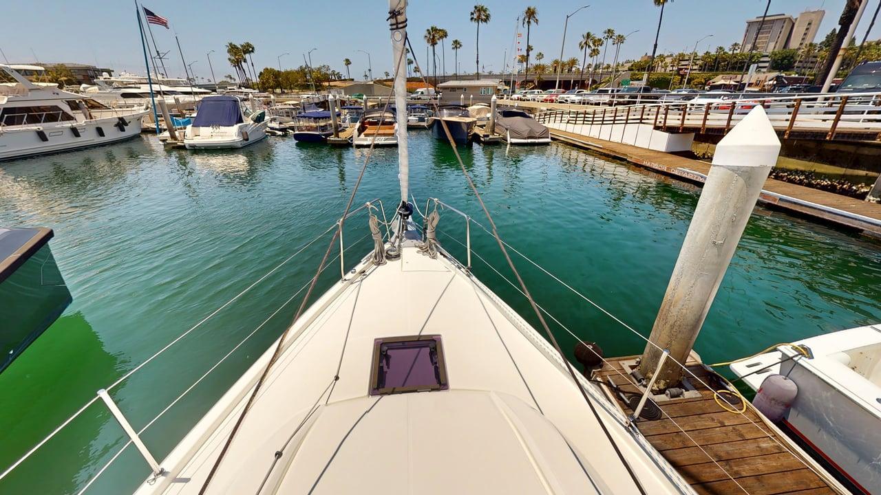 Bow view of 2021 Beneteau Oceanis 40.1 yacht docked in a marina with palm trees.