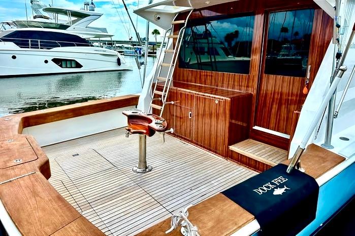 1998 Viking 50 Convertible yacht with wooden deck and fishing chair in marina.
