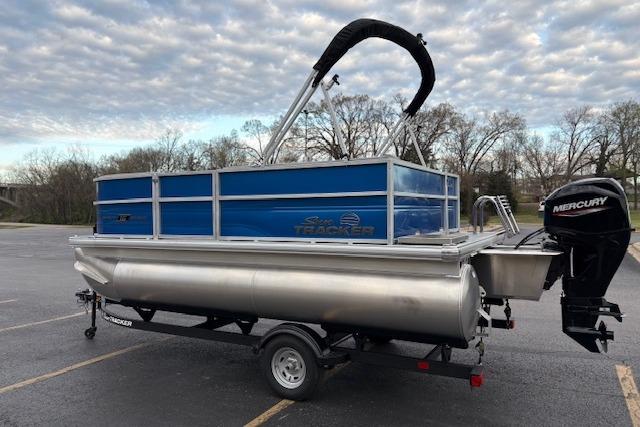 2026 Sun Tracker Party Barge 16 DLX pontoon boat with Mercury engine in parking lot.