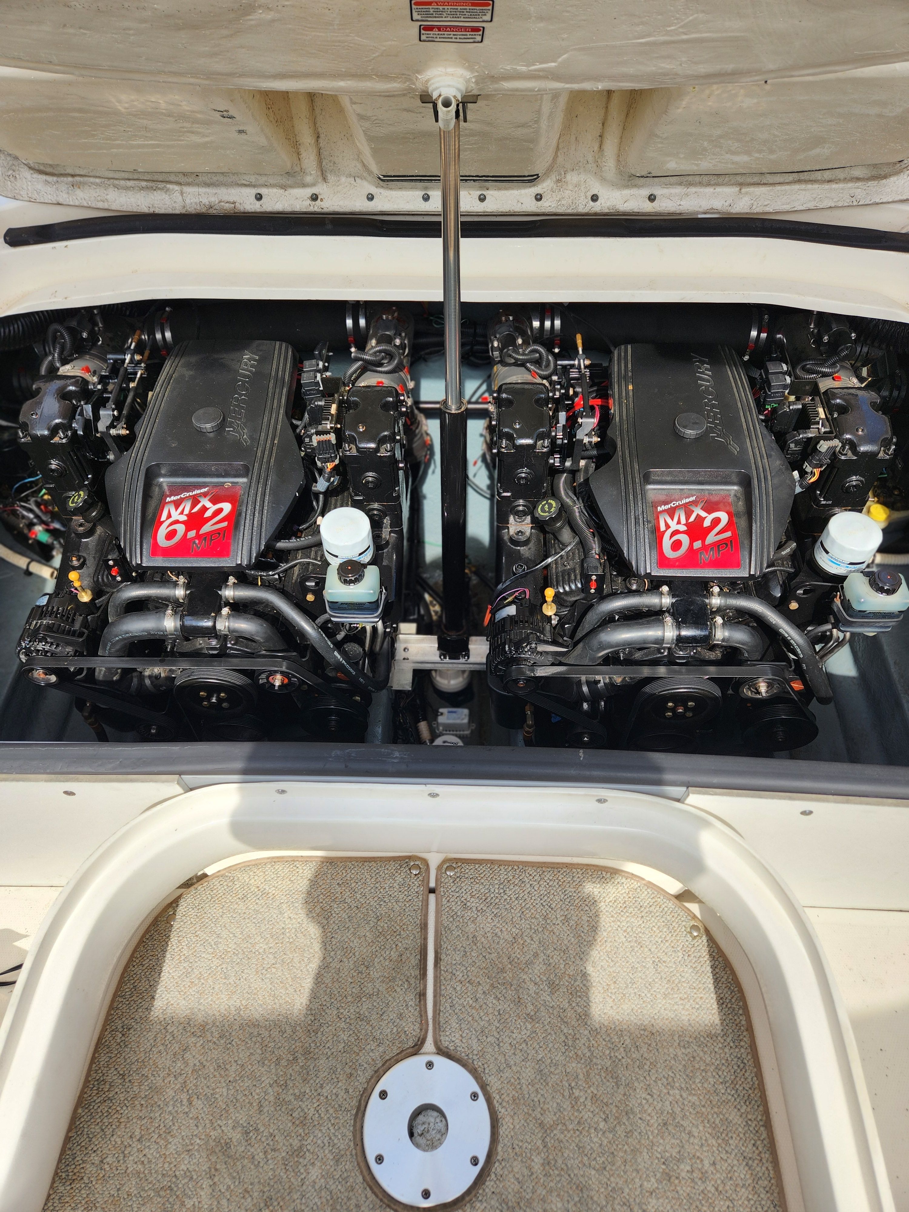 Two engines in a boat's engine compartment with an open cover.