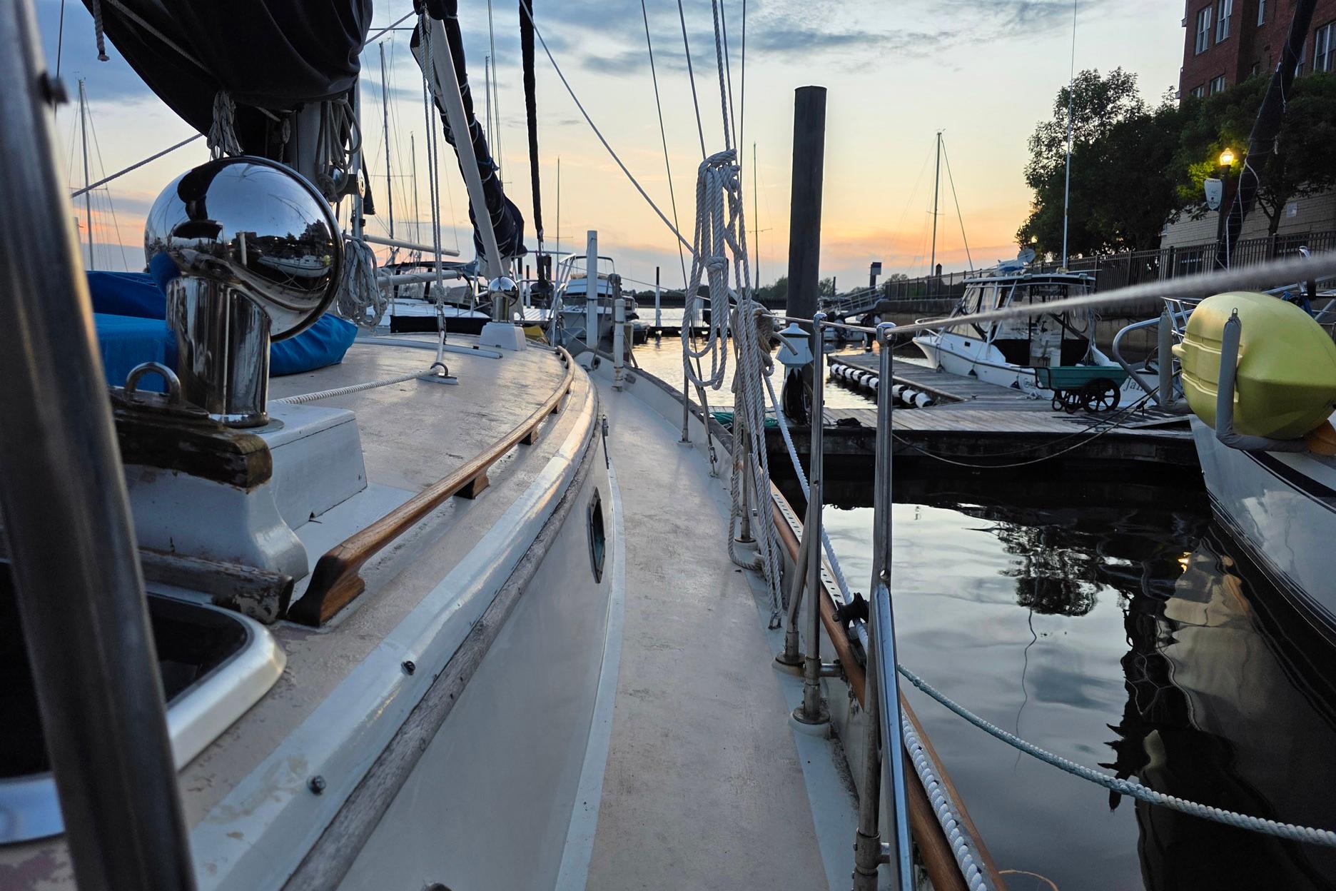 1982 Tayana 37 sailboat docked at sunset, reflecting on calm water.