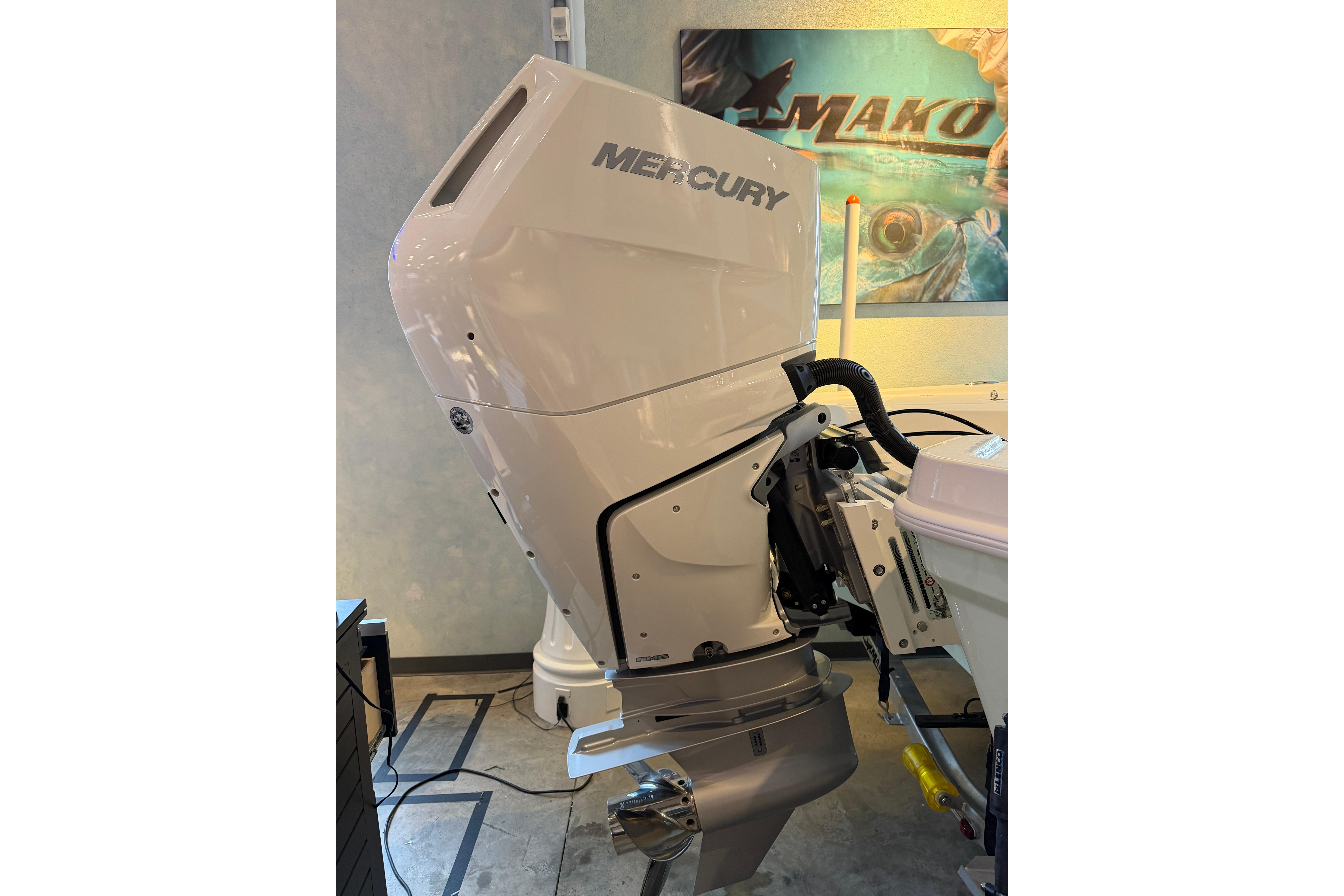 2026 Mako 24 APEX boat with Mercury outboard motor displayed indoors.