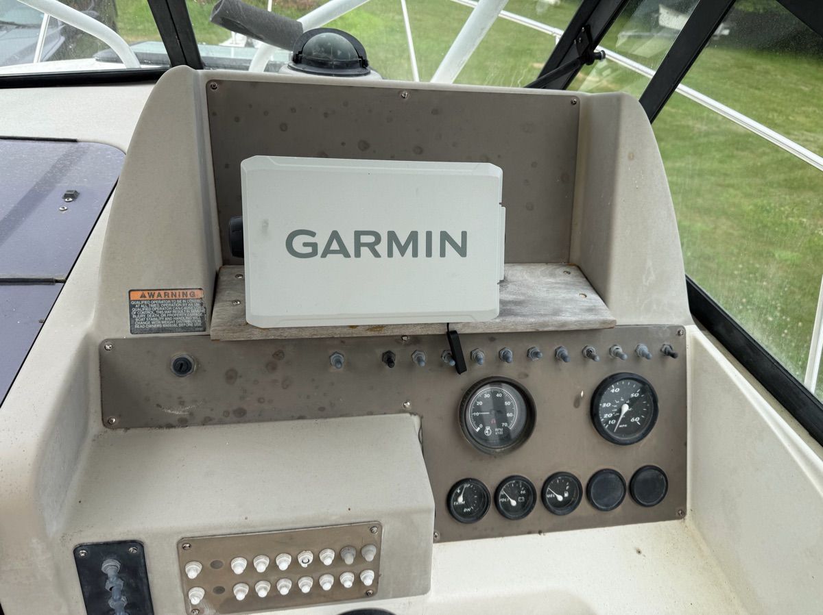 The image shows a boat's dashboard with a Garmin device and various instruments.