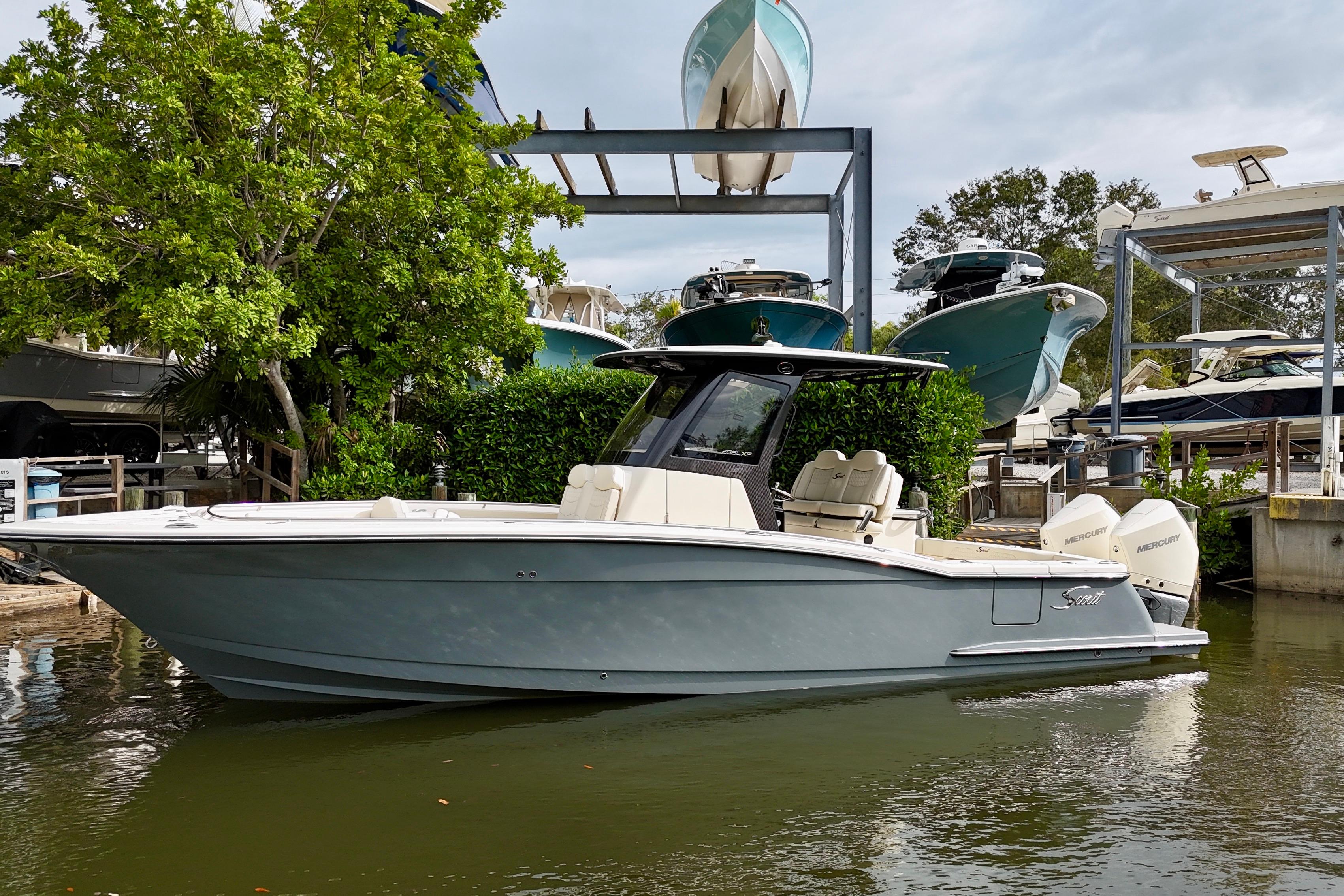 2026 Scout 288 LXF boat docked in marina, surrounded by lush greenery and other boats.