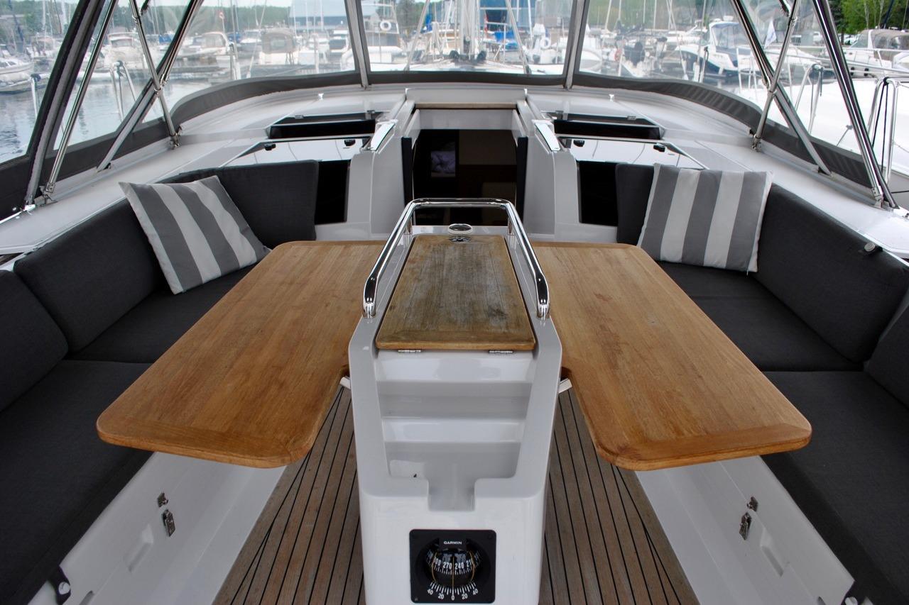 Spacious cockpit of 2017 Hanse 505 yacht with wooden tables and cushioned seating.