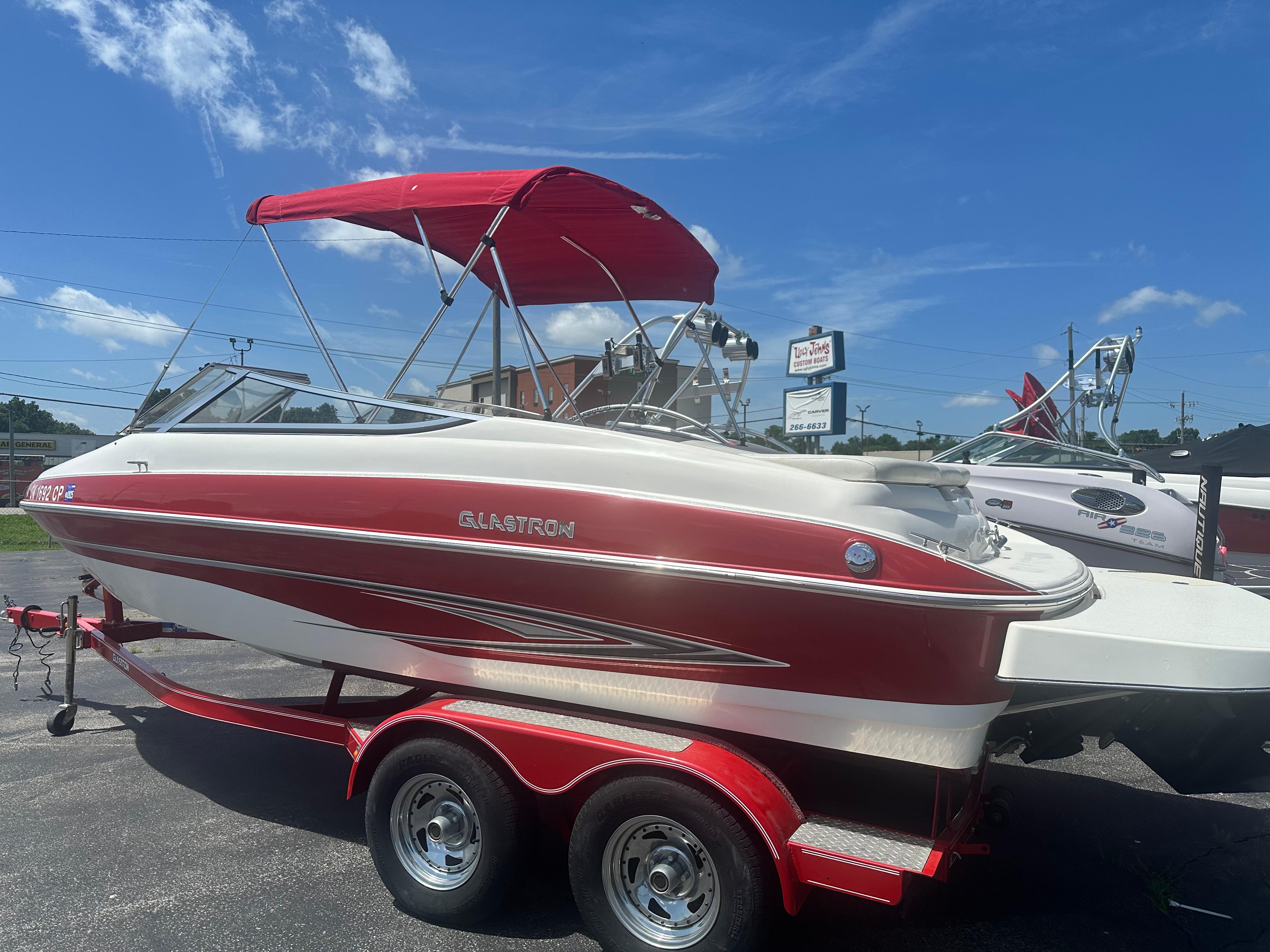 2008 Glastron 205 GX boat with red and white design on a trailer under blue sky.