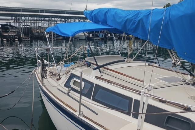 1989 O'Day 272 sailboat docked with blue sail cover, marina background.