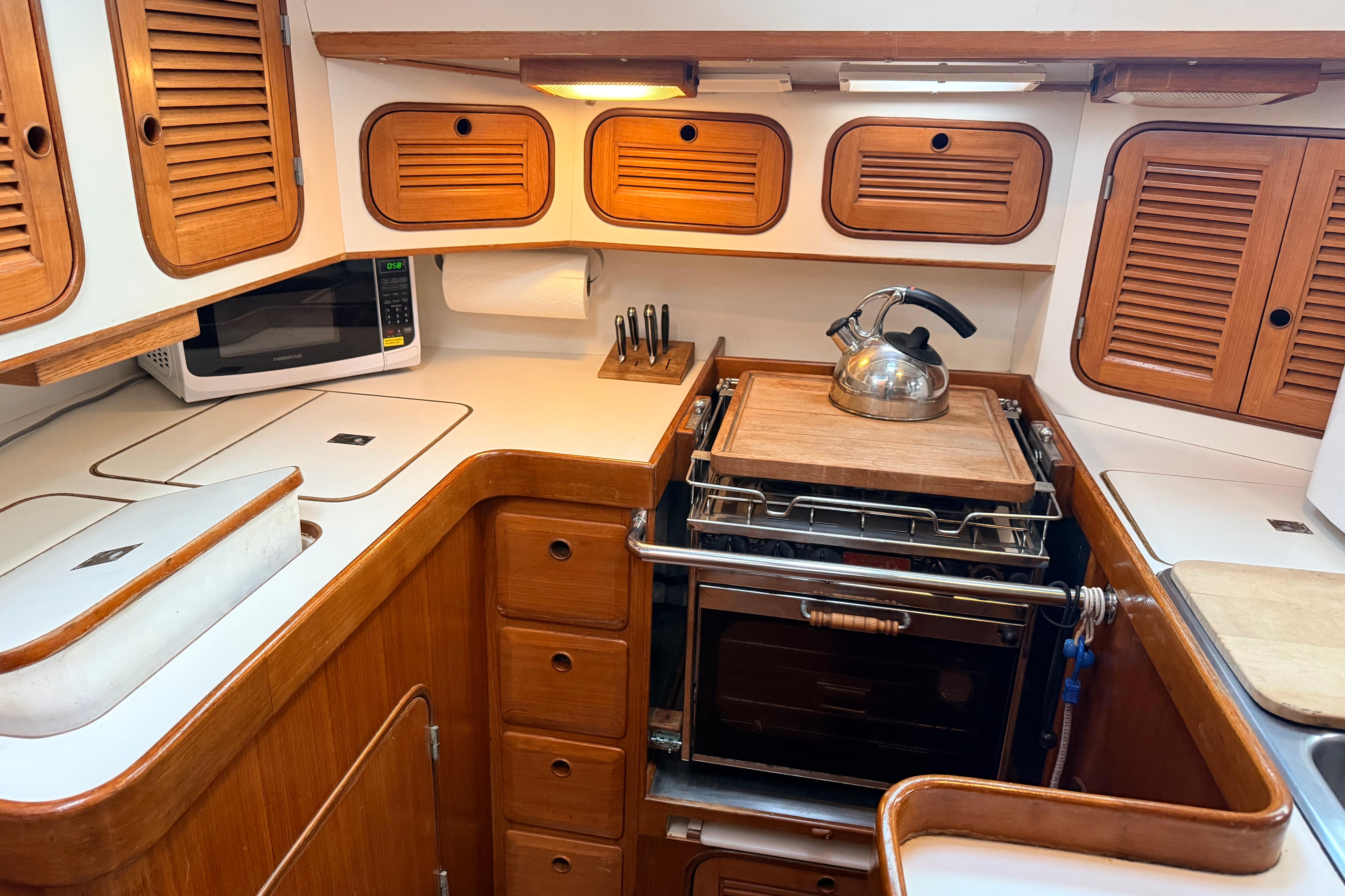 Compact kitchen in 1987 Norseman 400 yacht with wooden cabinets and modern appliances.
