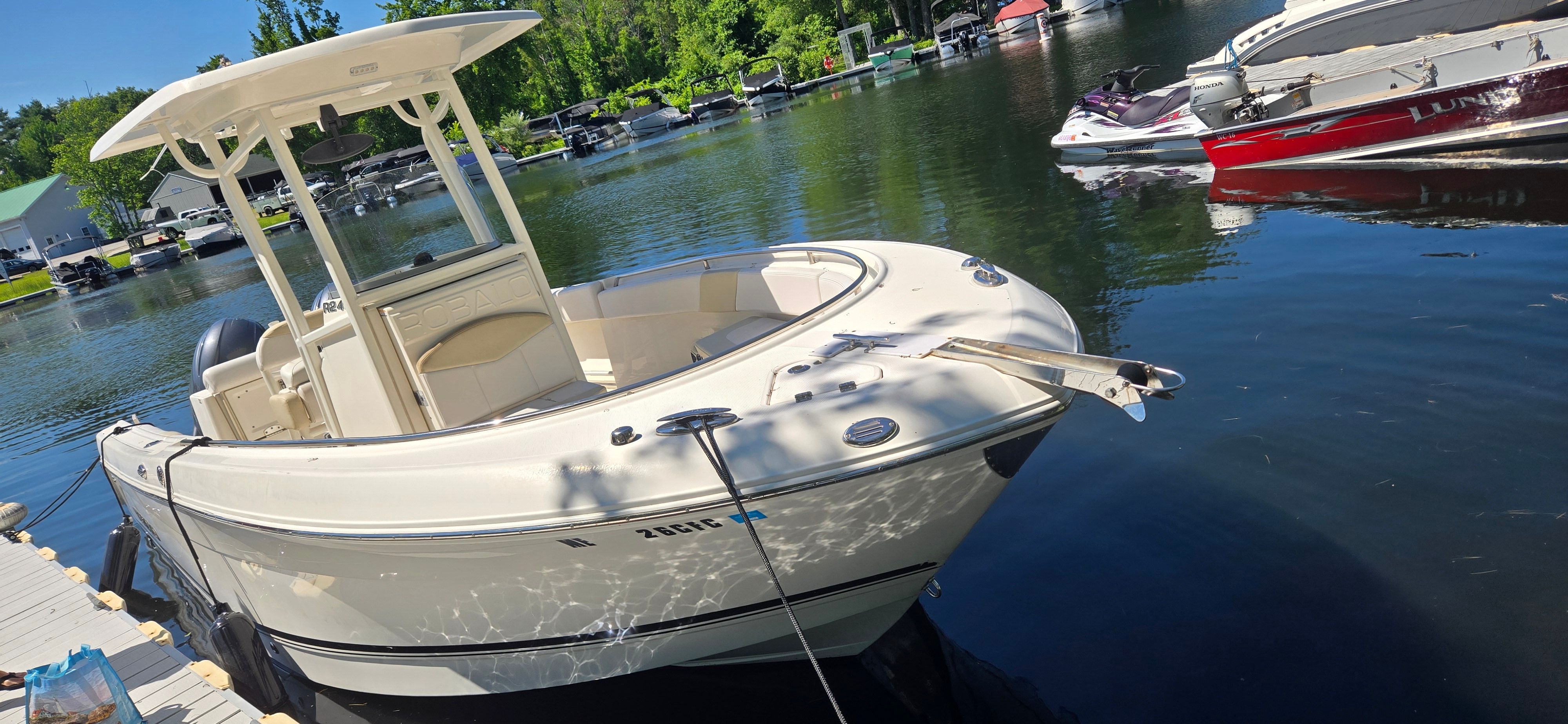 A 2016 Robalo R242 Center Console boat docked in a calm marina.