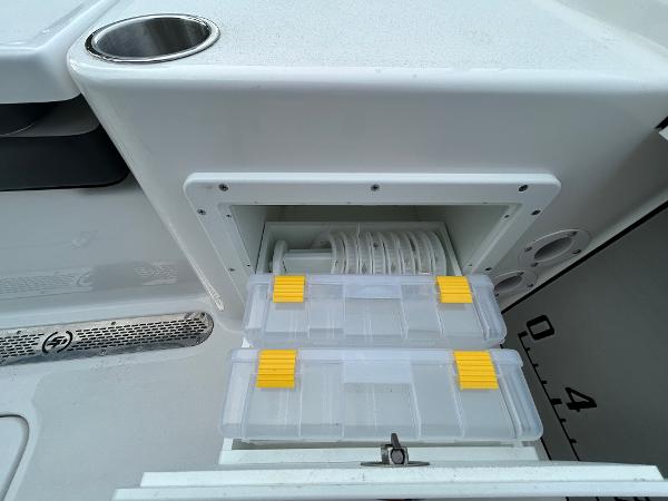 Storage compartment on 2024 Sea Pro 250 DLX boat with tackle boxes and cup holder.