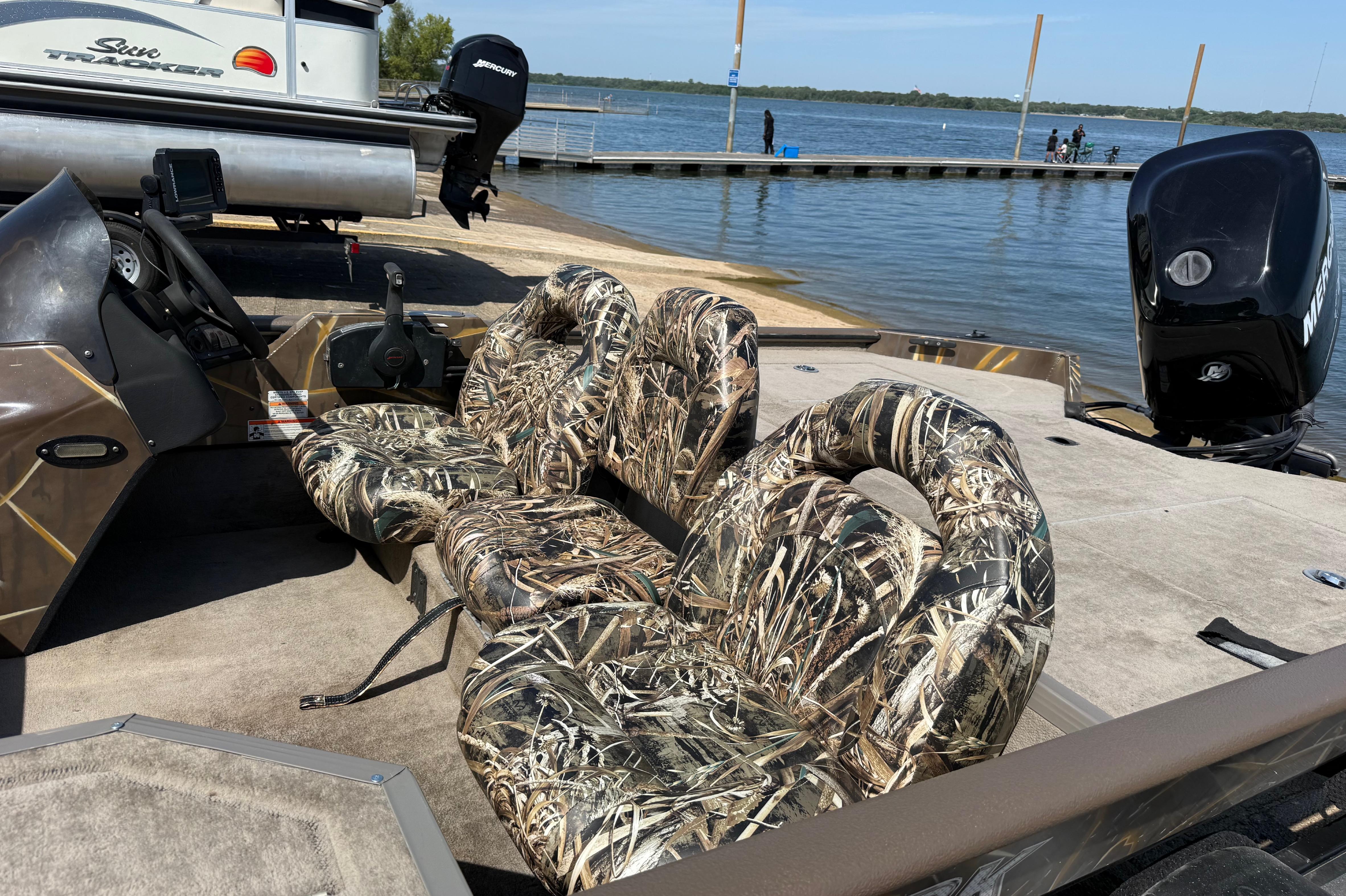 2010 SeaArk Stealth 190 boat with camouflage seats docked by a lake.