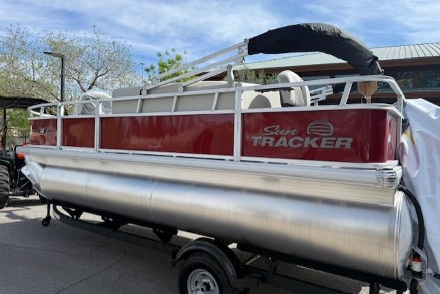 2026 Sun Tracker Bass Buggy 18 DLX pontoon boat on trailer, parked outdoors.