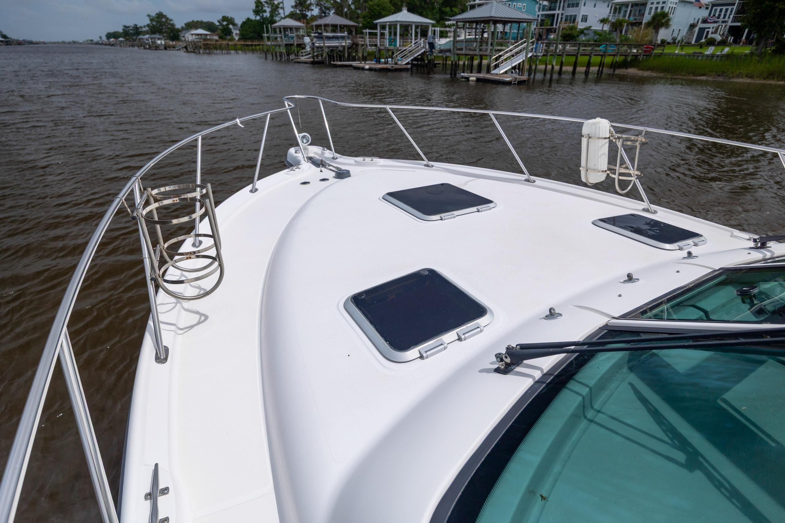 2004 Tiara Yachts 3200 Open boat deck with hatches, docked near waterfront homes.
