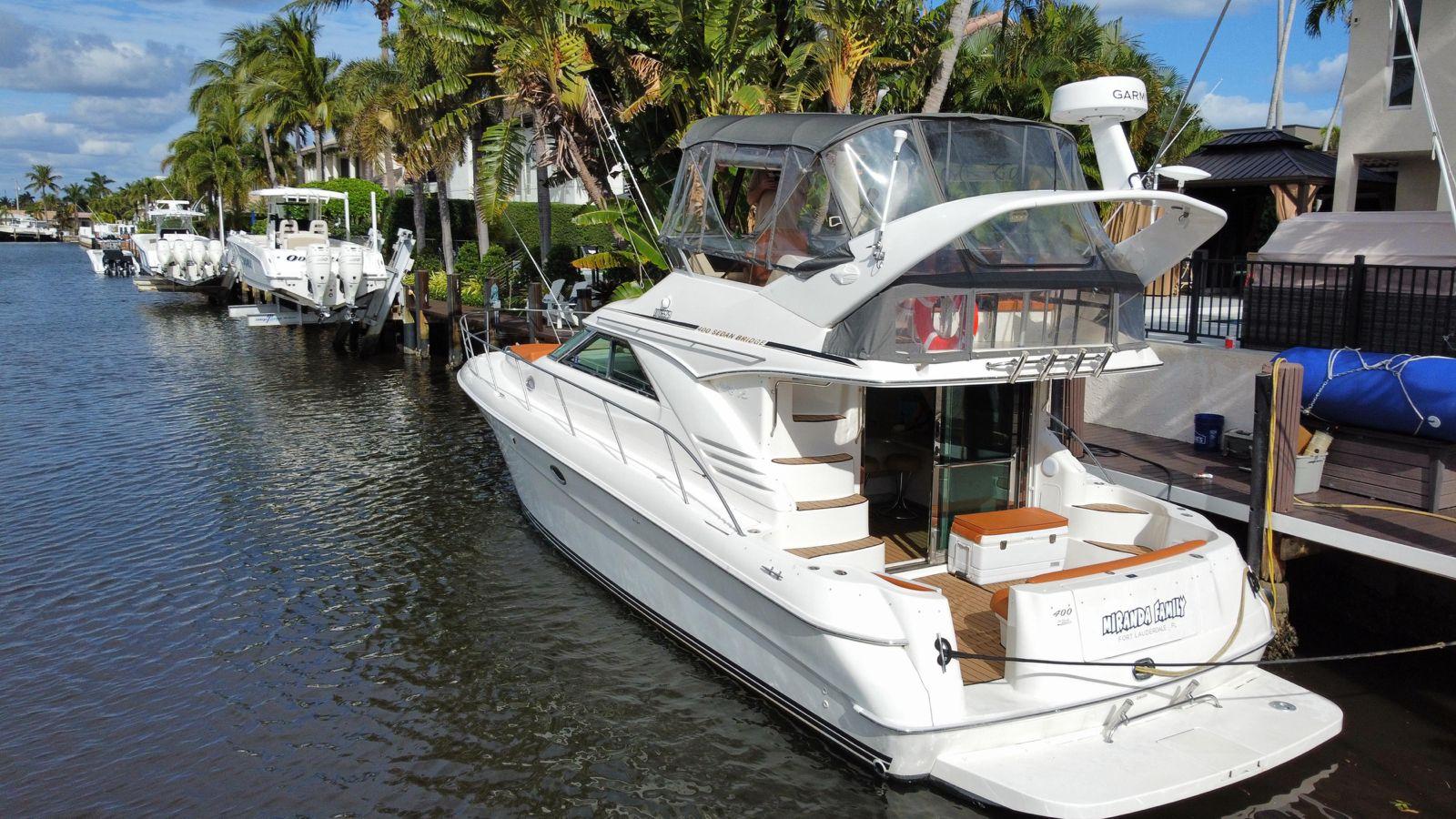 1997 Sea Ray 400 Sedan Bridge yacht docked by palm trees and waterfront homes.