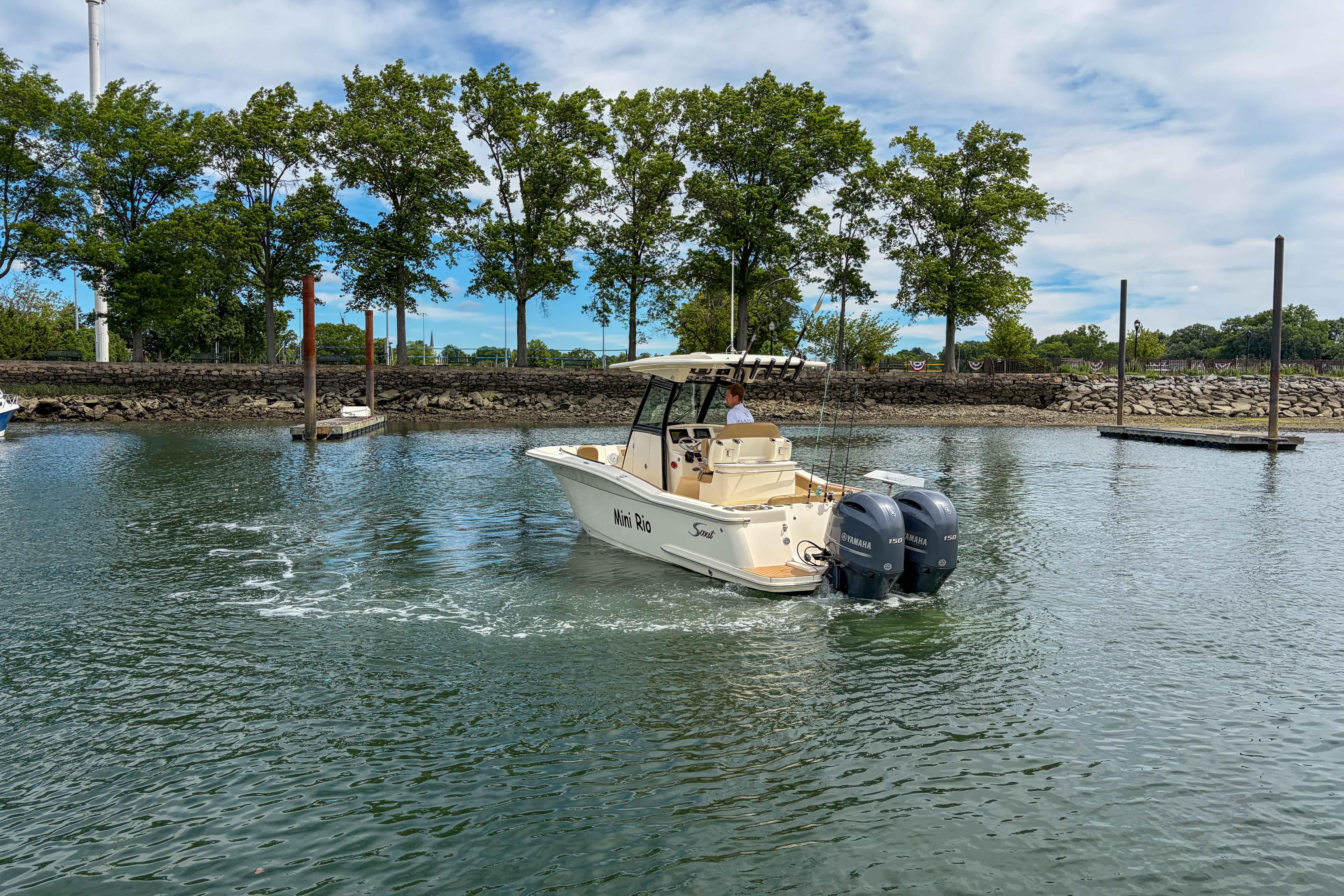2020 Scout 255 LXF boat cruising on a calm lake with trees in the background.
