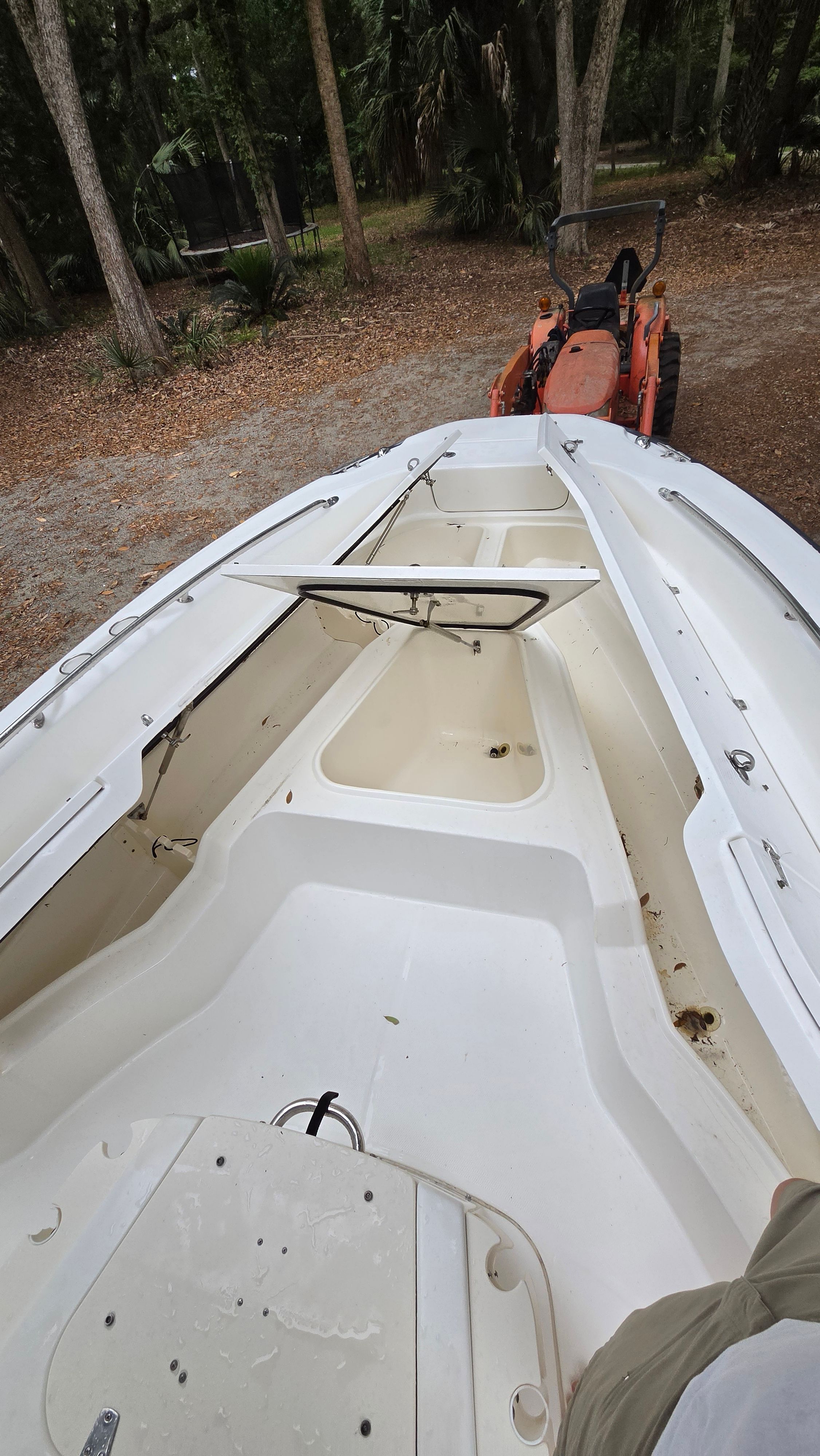 A 2008 Boston Whaler 230 Dauntless on a trailer outdoors, surrounded by trees.