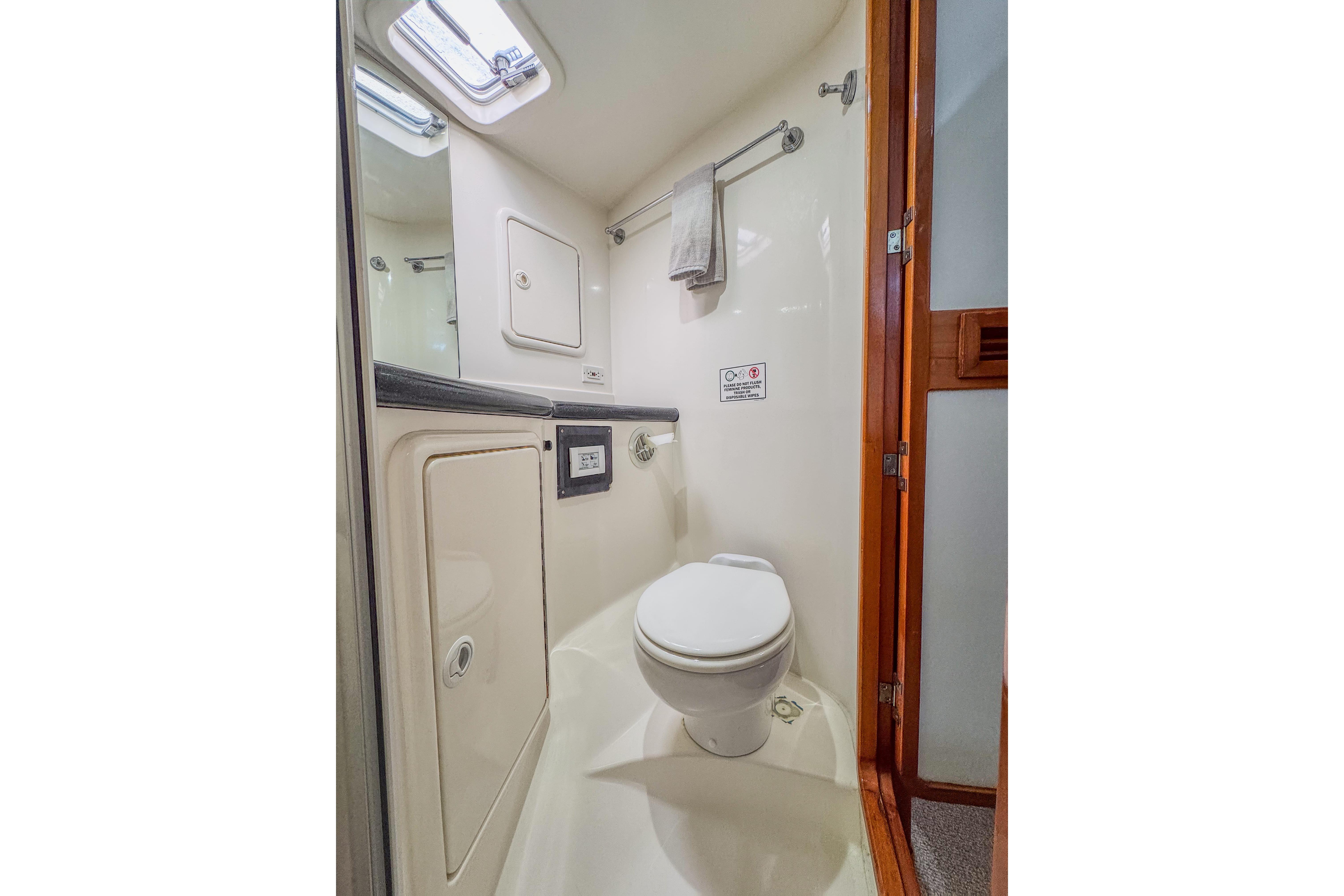 Compact bathroom in 2001 Black Watch 40 yacht, featuring toilet and storage.