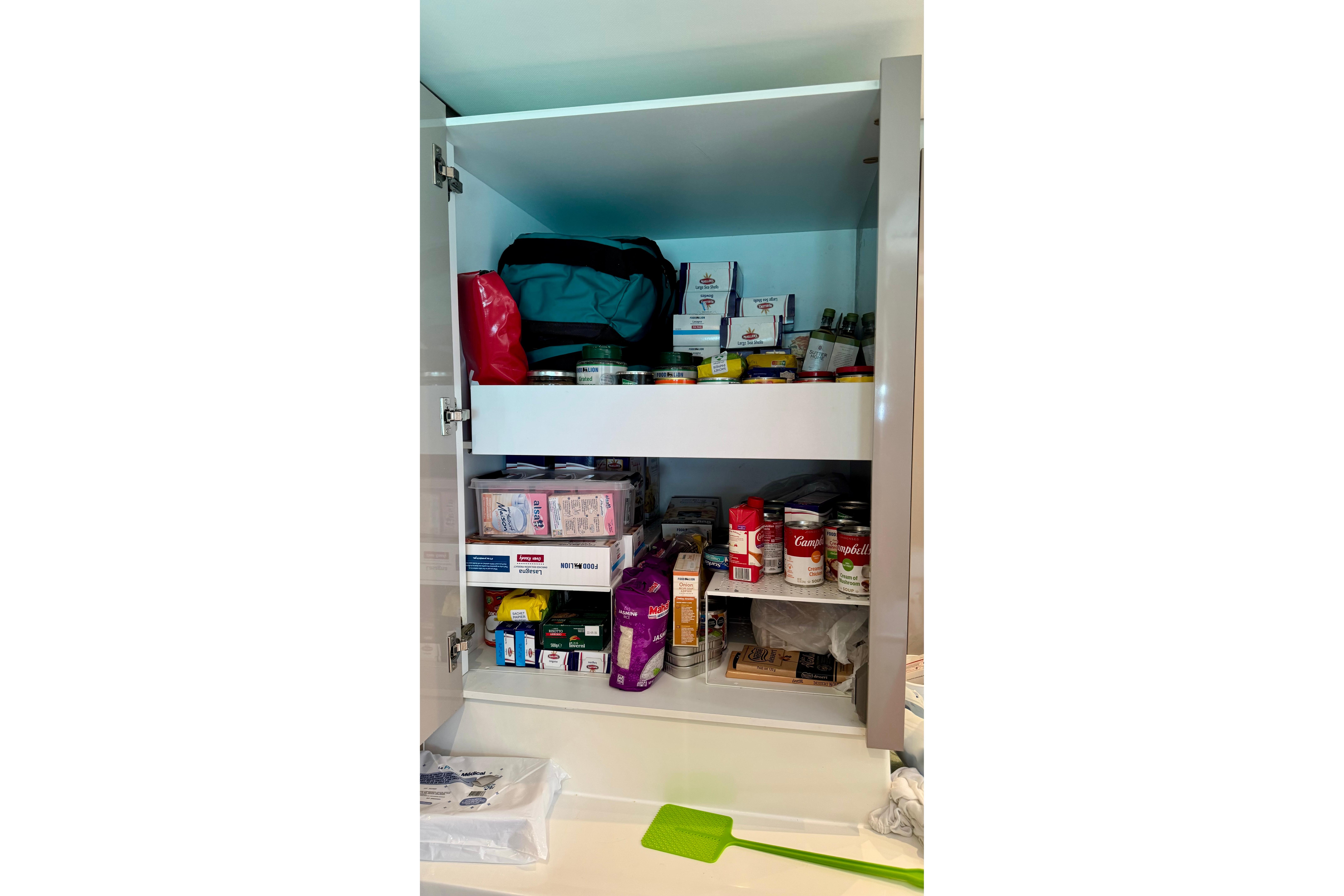 Pantry cabinet on Fountaine Pajot Saona 47 yacht, stocked with canned goods and packaged food.