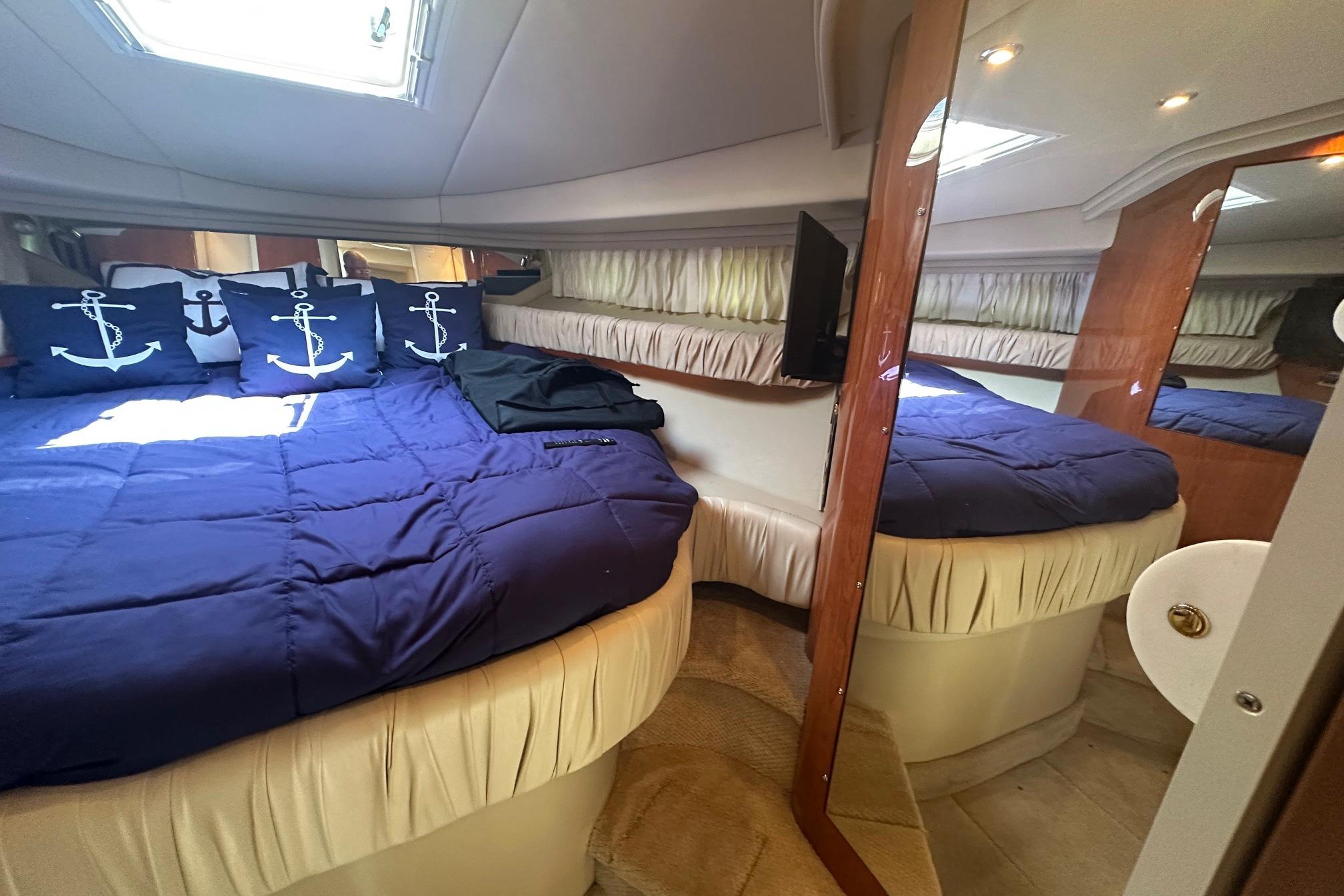 Luxurious cabin interior of 2001 Sea Ray 410 Sundancer with nautical-themed bedding.