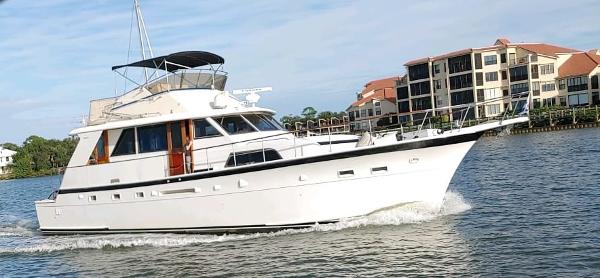 A white yacht cruising on a river, surrounded by residential buildings.