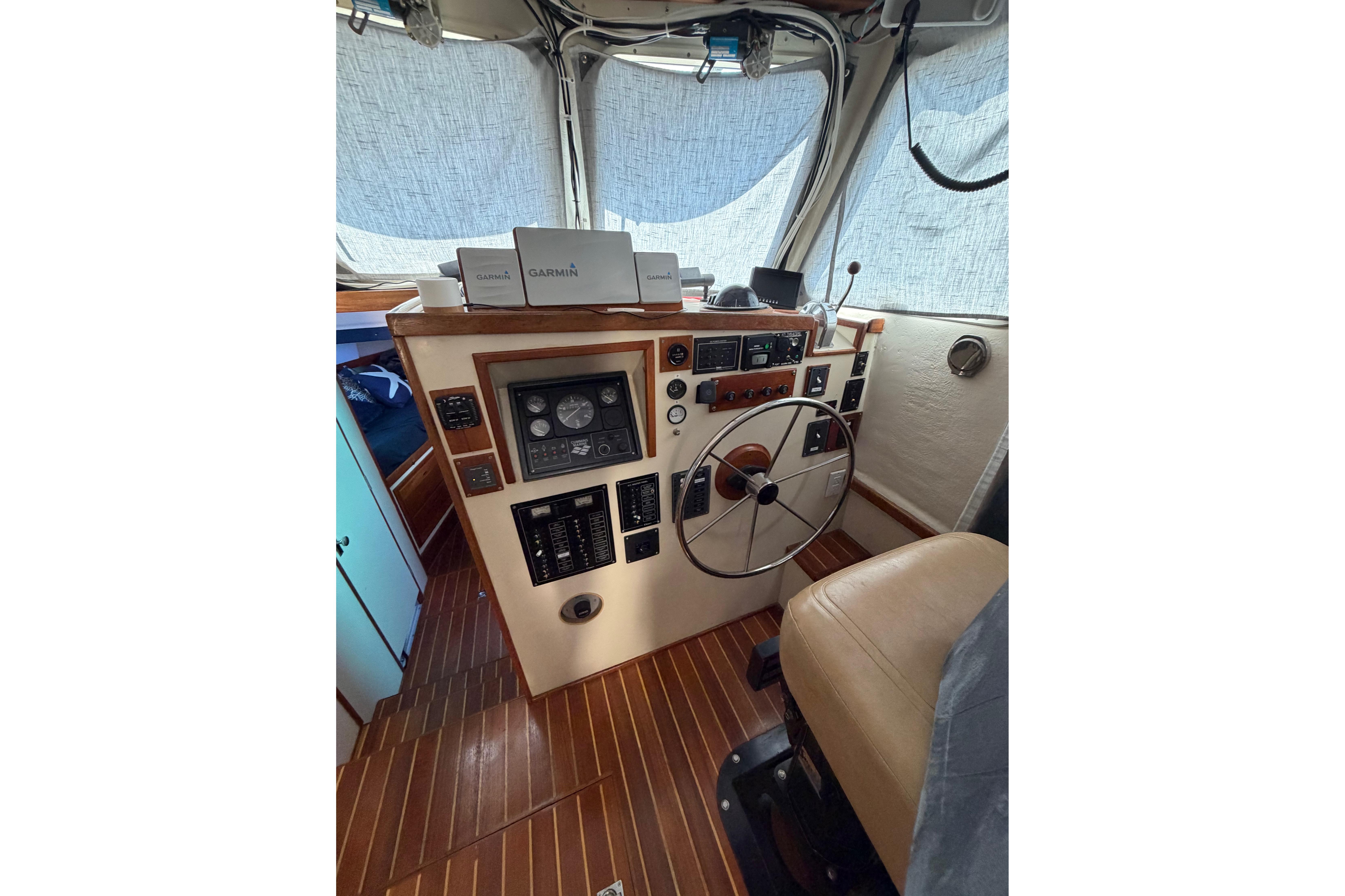 1997 Rosborough Trawler helm with Garmin navigation, featuring classic wood paneling and steering wheel.