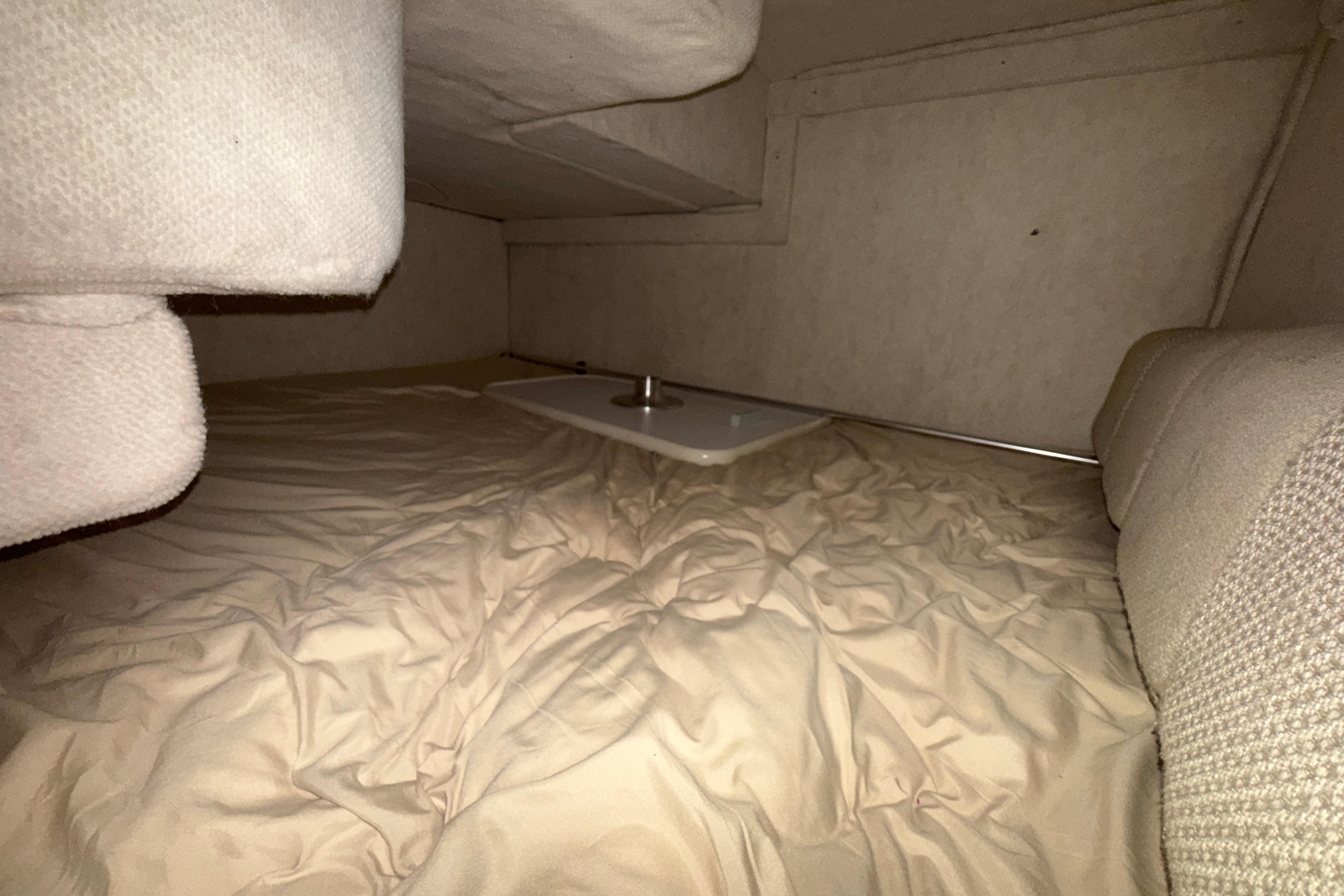Interior cabin of 2004 Sea Ray 240 Sundancer with beige upholstery and compact sleeping area.