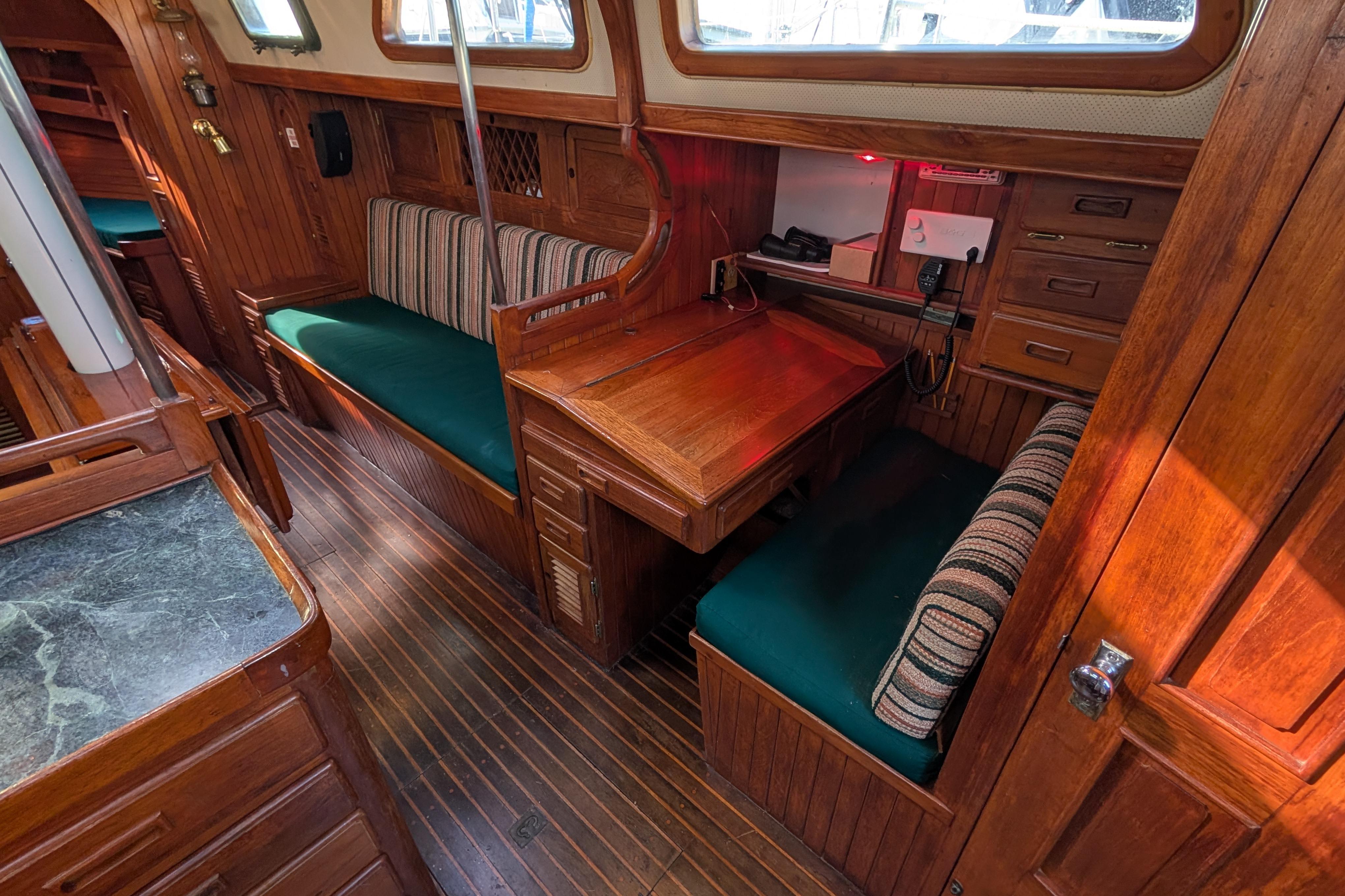 Interior of 1983 Robert Perry 41 sailboat with wooden furnishings and green cushions.