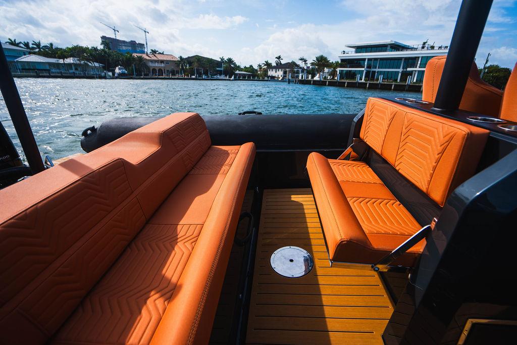 Luxurious 2025 Onda Magna boat interior with orange seating, docked by waterfront homes.