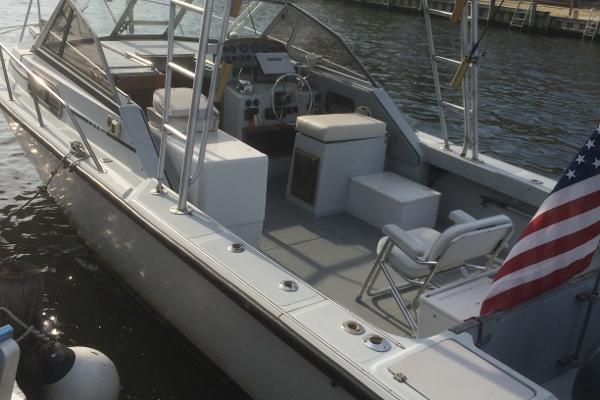 1987 Boston Whaler Cuddy Tower boat docked, featuring spacious seating and American flag.