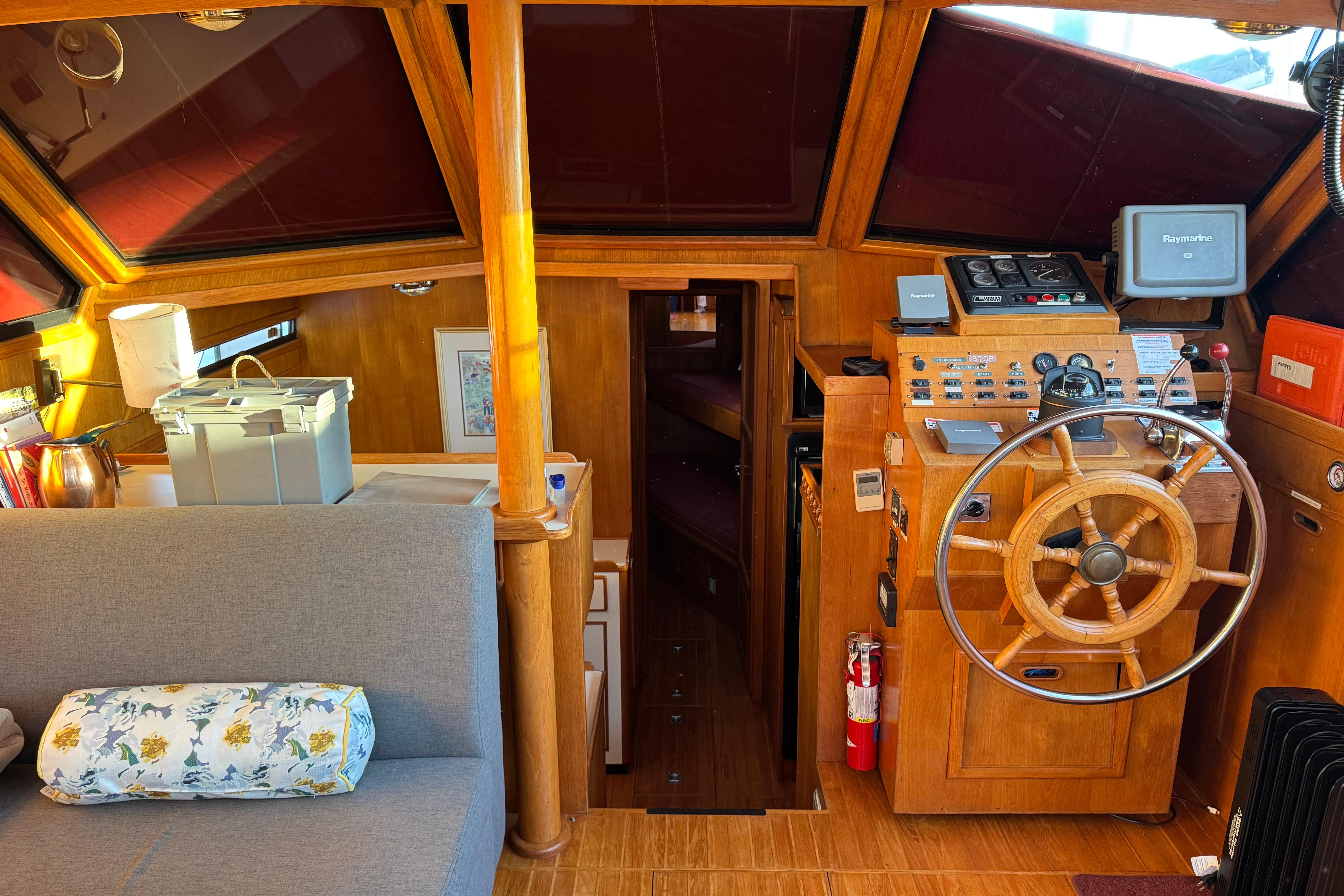 Cozy 1987 President 37 yacht interior with wooden helm, seating, and navigation equipment.