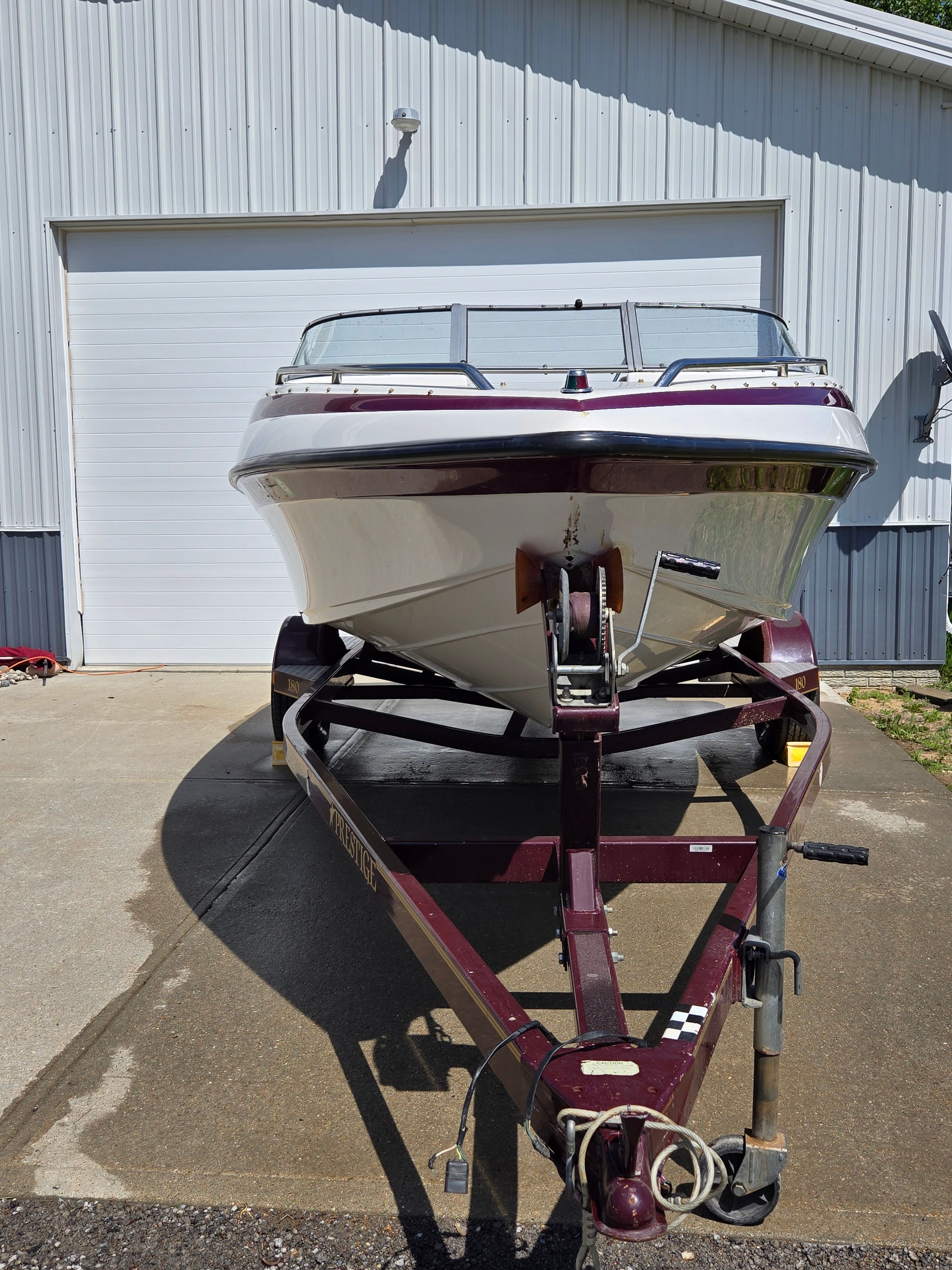 A 2001 Crownline 180 BR boat on a trailer in front of a garage.