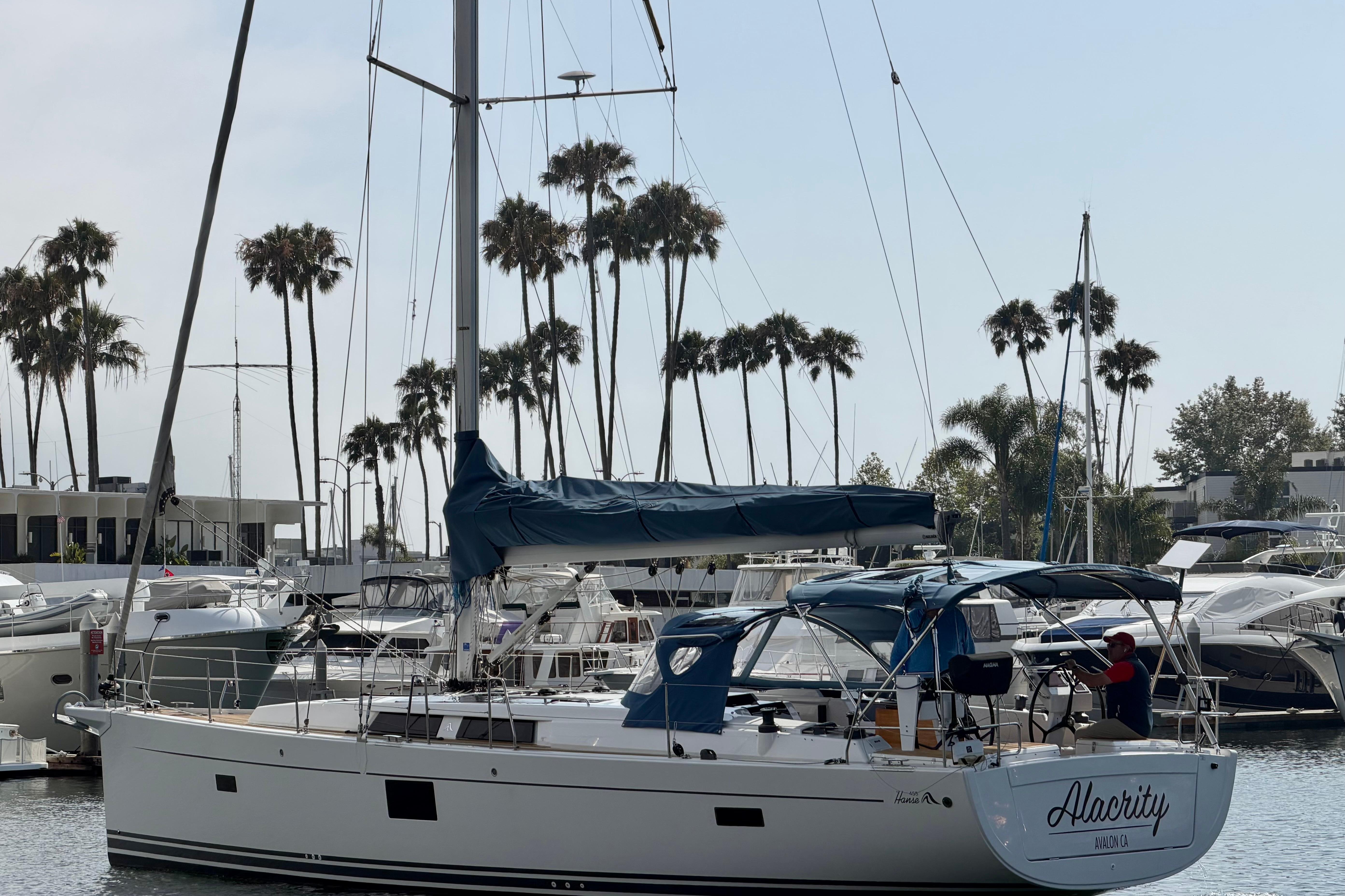2016 Hanse 455 sailboat docked in marina with palm trees in background.
