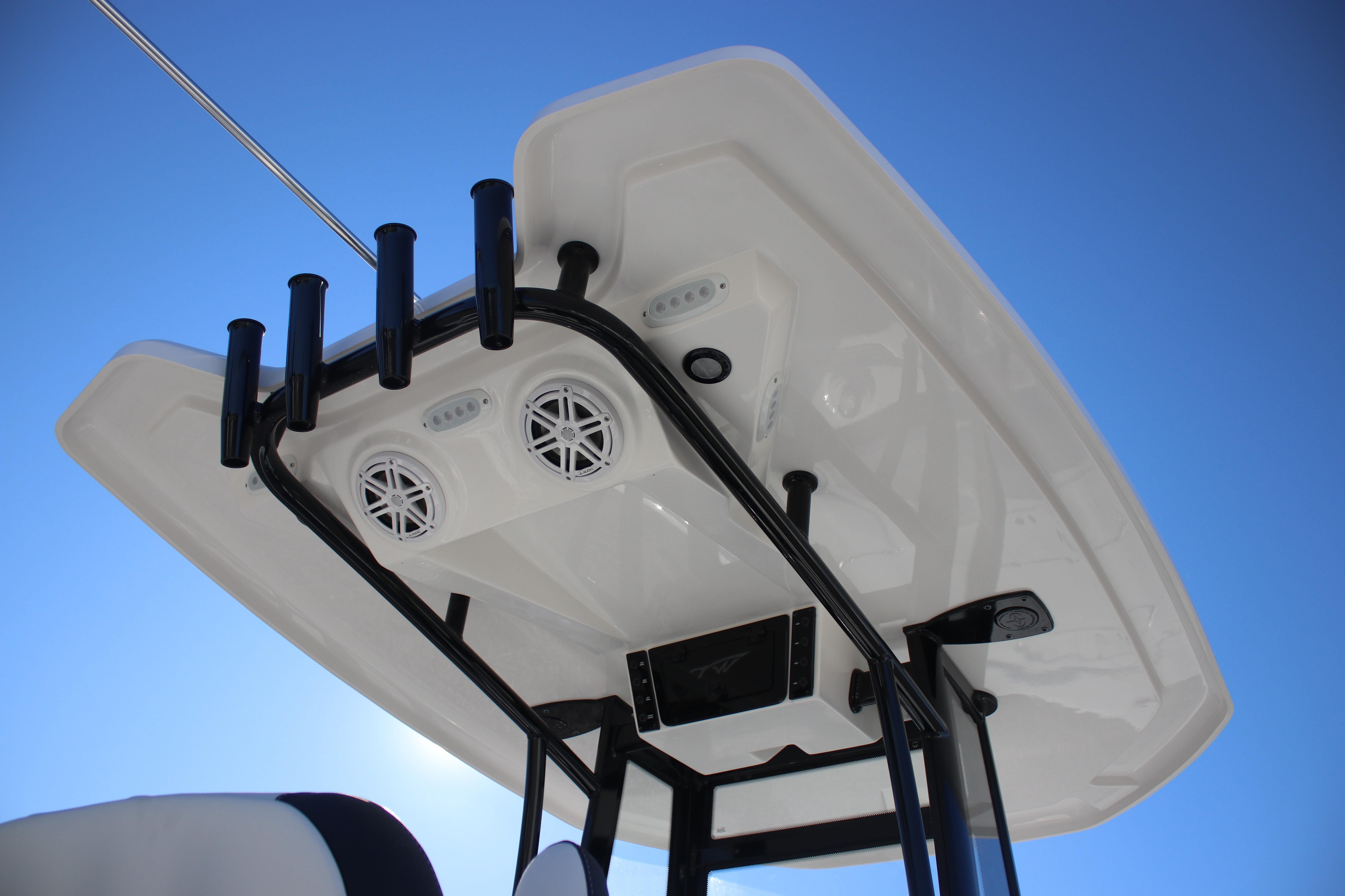 2026 Tidewater 2210 Carolina Bay boat T-top with speakers and rod holders against blue sky.