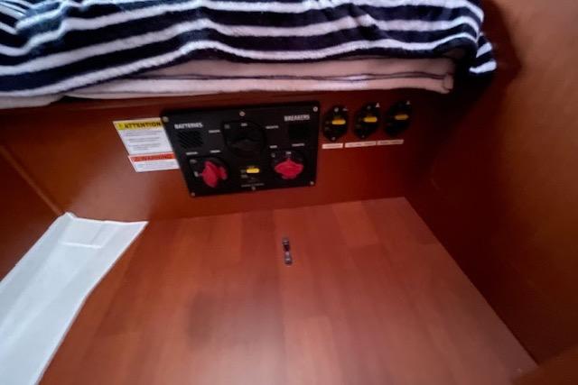 Electrical panel inside 2018 Beneteau Oceanis 45 yacht cabin with striped blanket above.