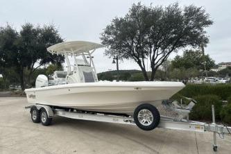 2026 Mako 24 APEX boat on trailer, parked outdoors with trees in background.