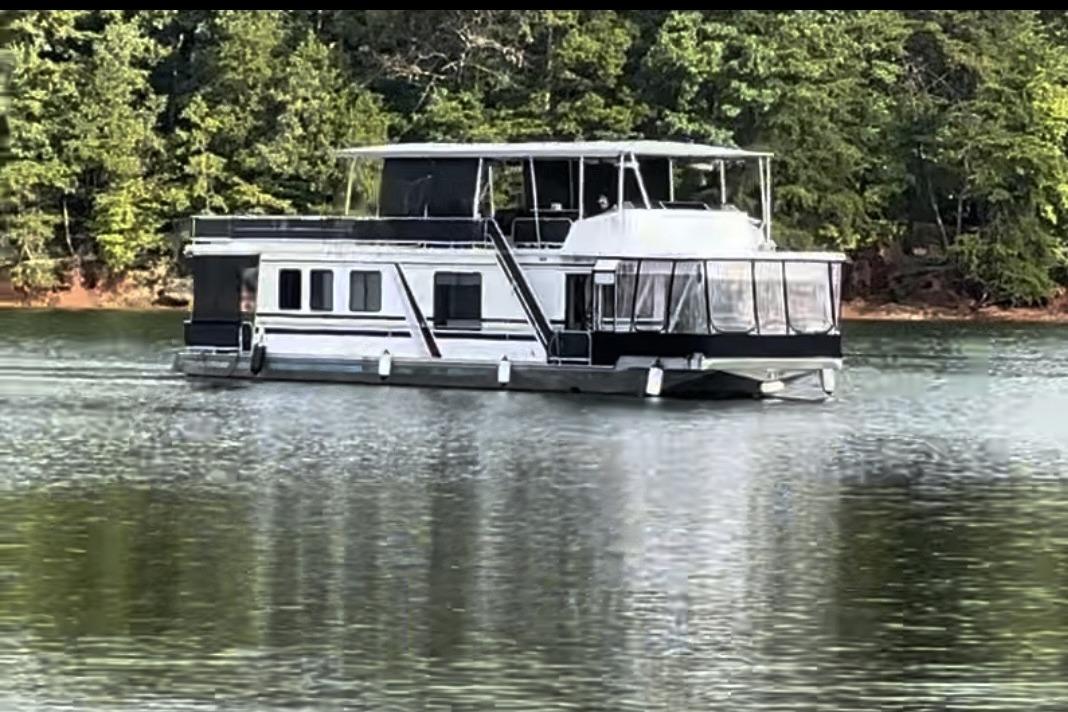 1992 Sumerset 66 houseboat on a calm lake with forested shoreline.