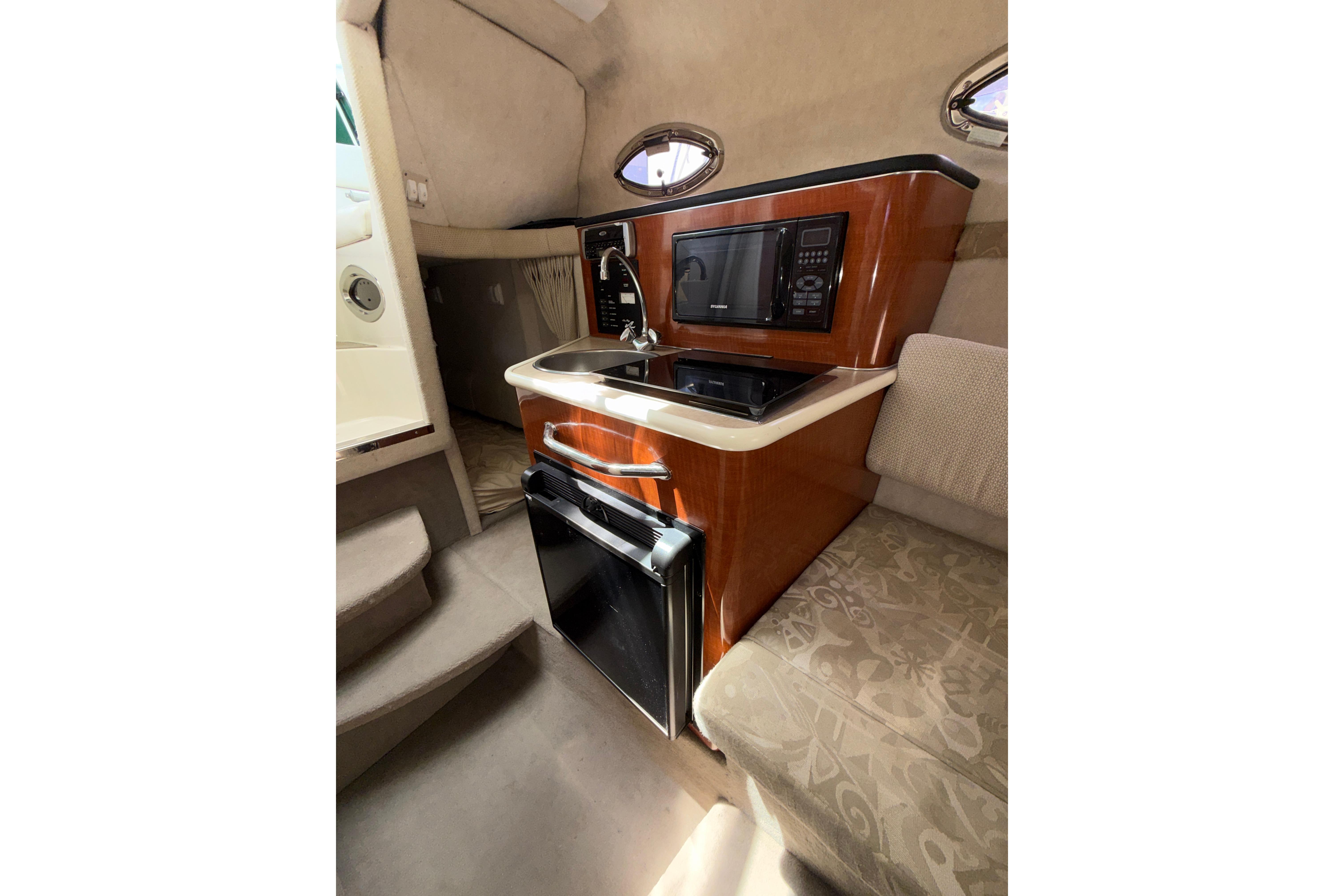 Interior of 2004 Sea Ray 240 Sundancer boat with kitchenette and seating area.
