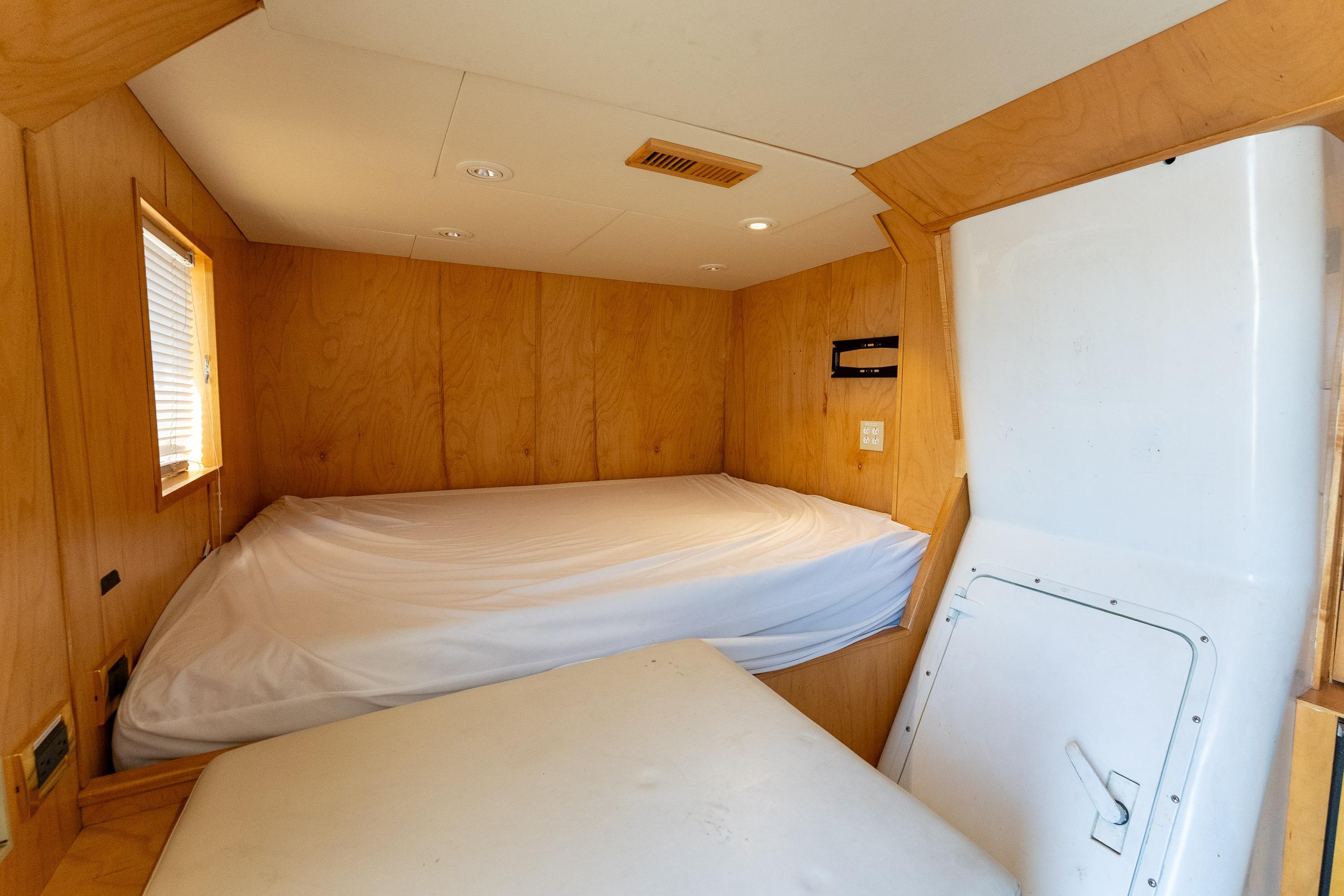 Cozy cabin interior of 1985 Delta Marine Expedition Yacht with wooden paneling and bed.