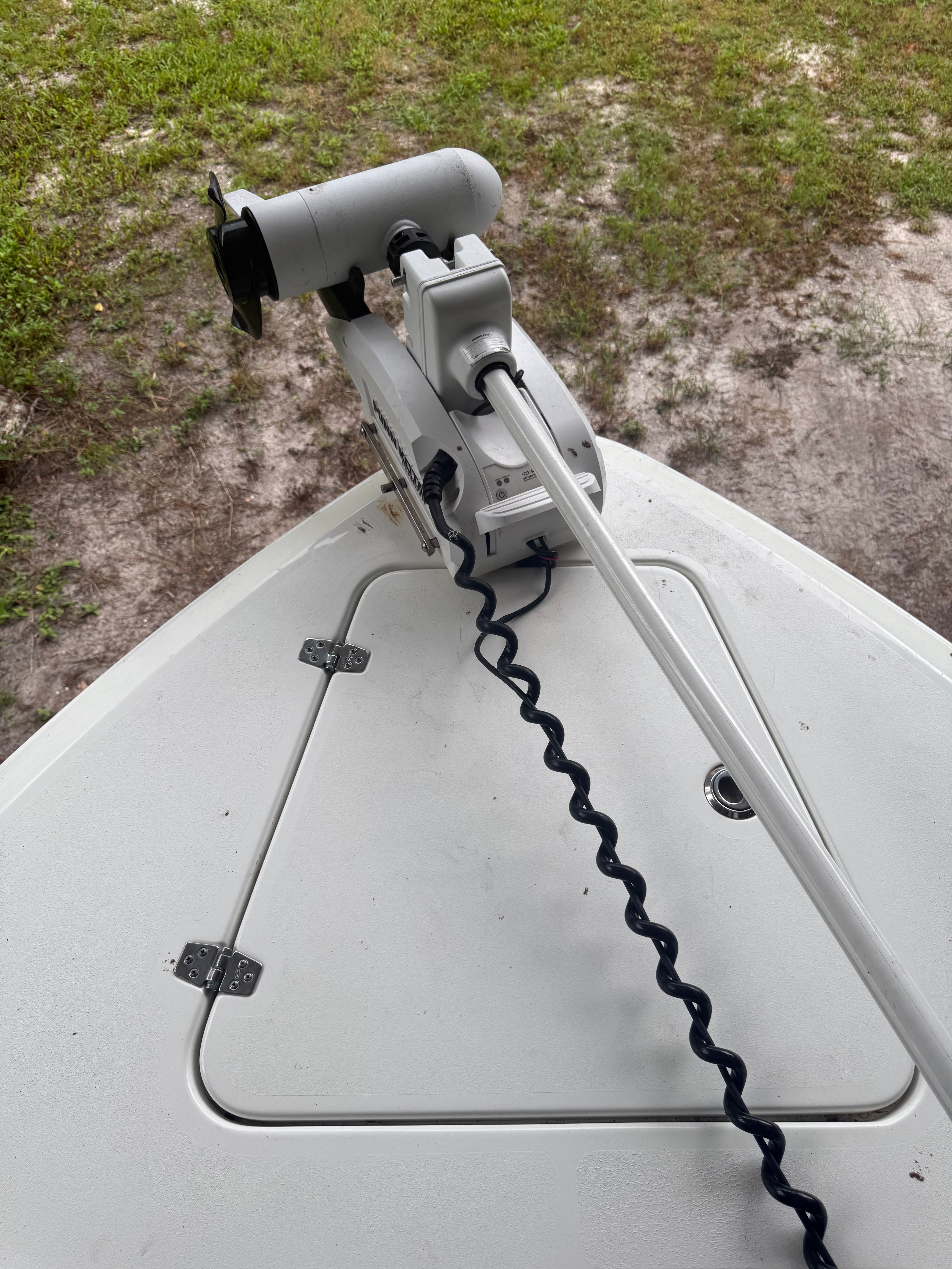Bow of a boat with a mounted electric motor and storage hatch.
