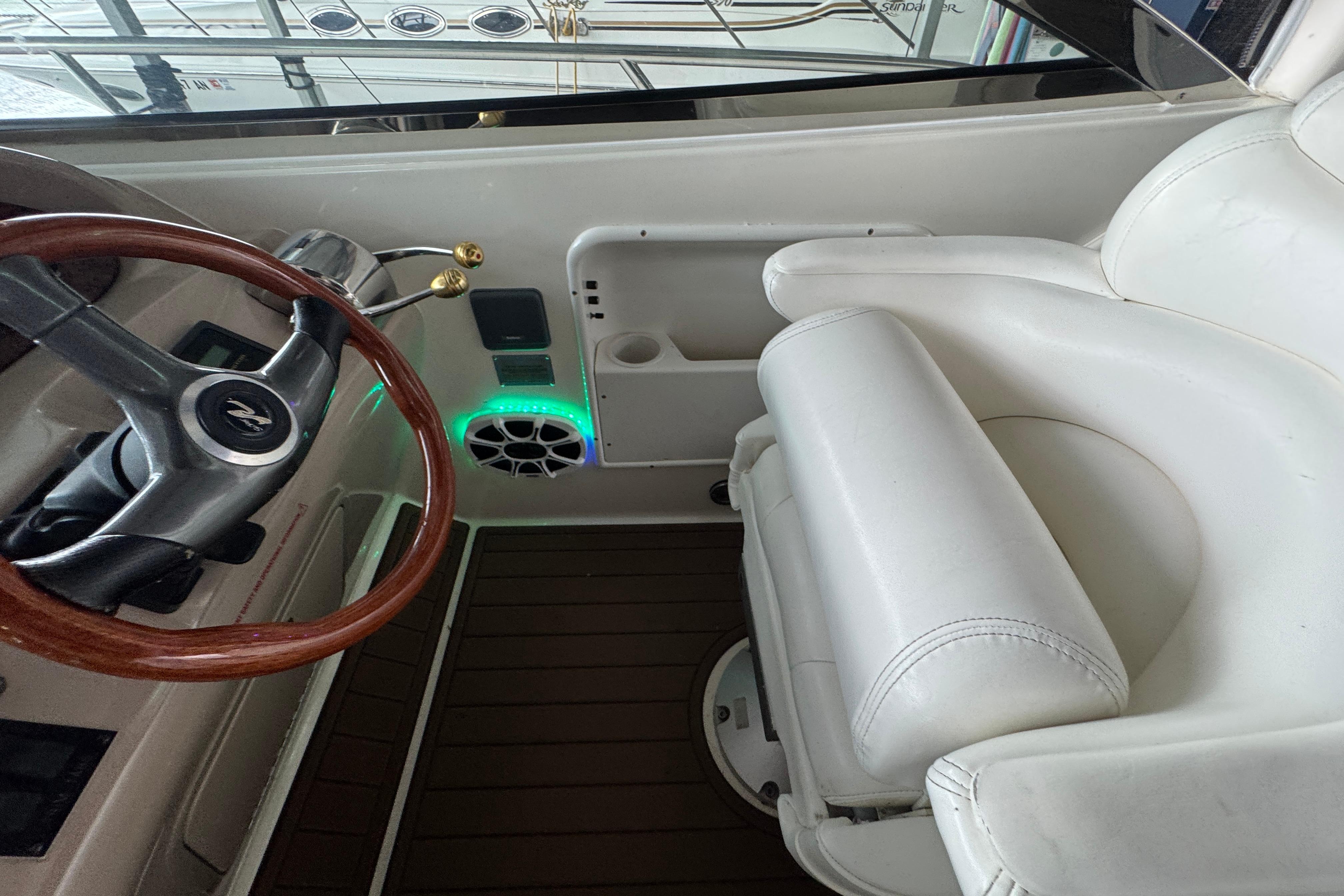 2001 Sea Ray 380 Sundancer helm with wooden steering wheel and white captain's chair.