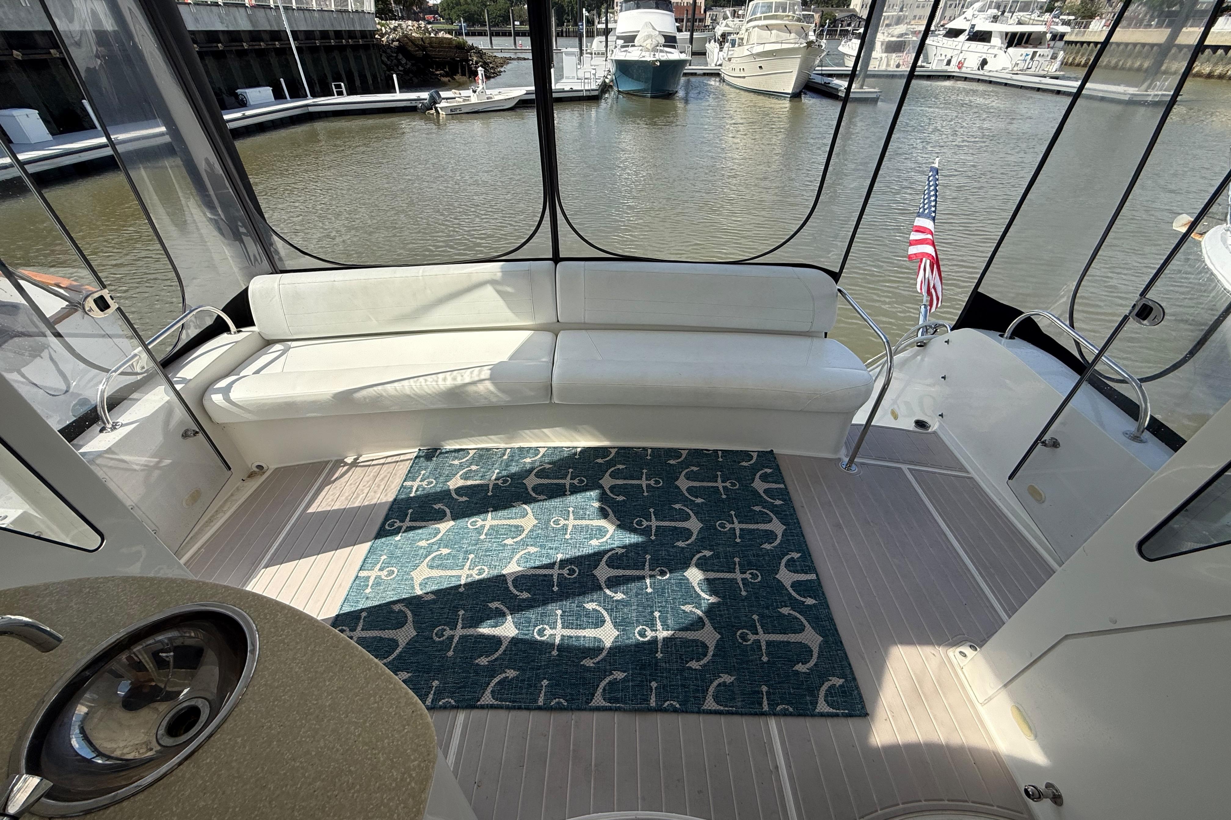 2006 Carver 43 Motor Yacht interior with white seating, anchor-patterned rug, and marina view.